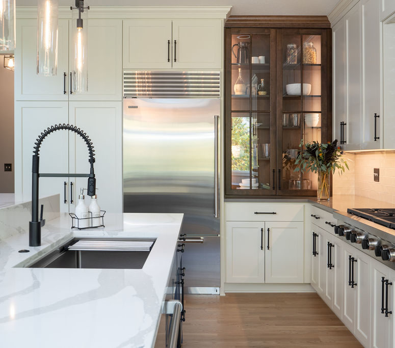 An Edina remodel featuring a white kitchen with stainless steel appliances and marble counter tops.