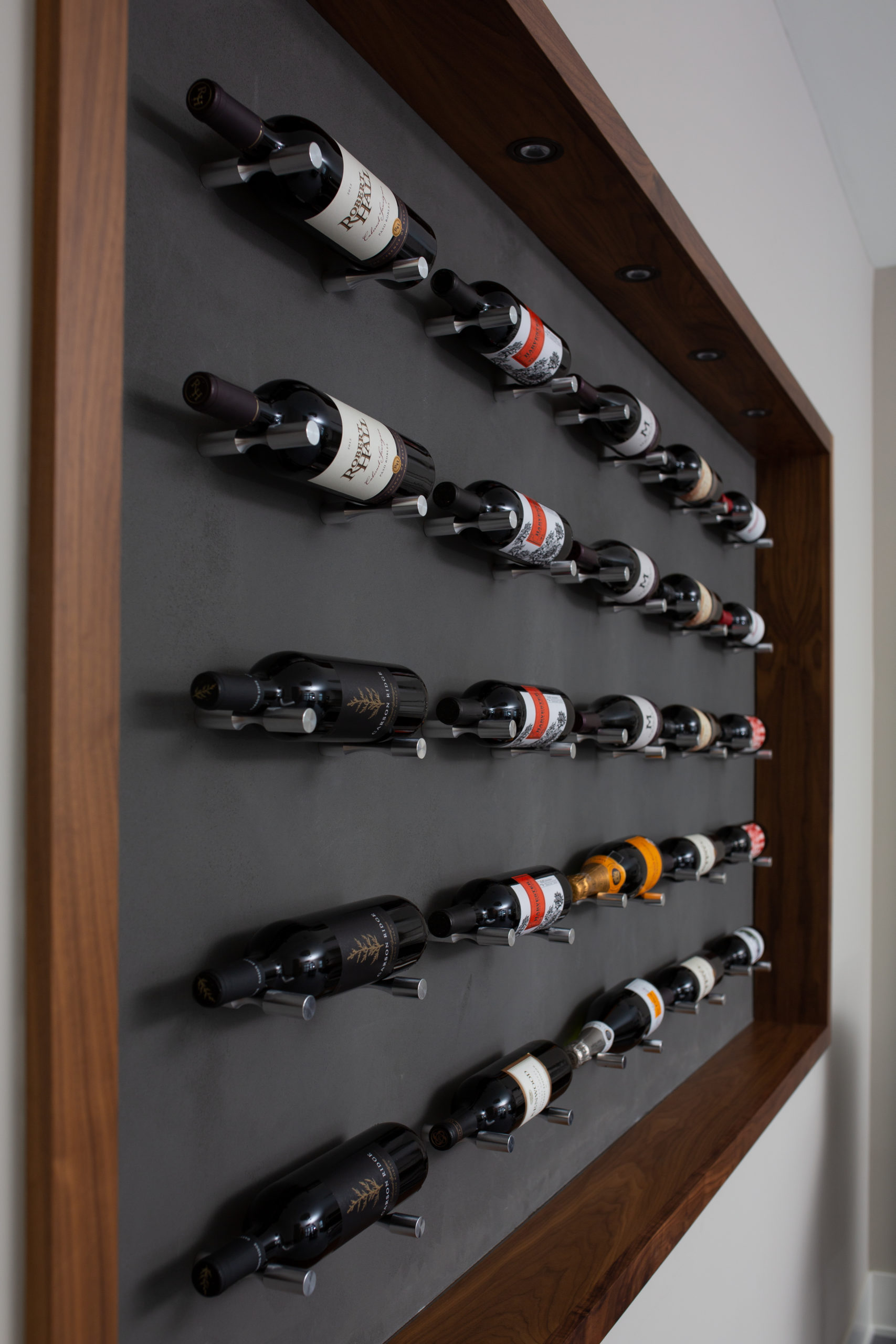 A wall mounted wine rack with wine bottles on it.