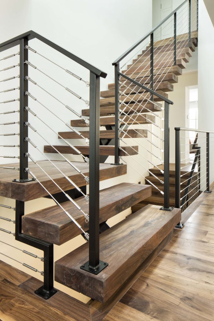 A modern staircase with metal railings and wood floors.