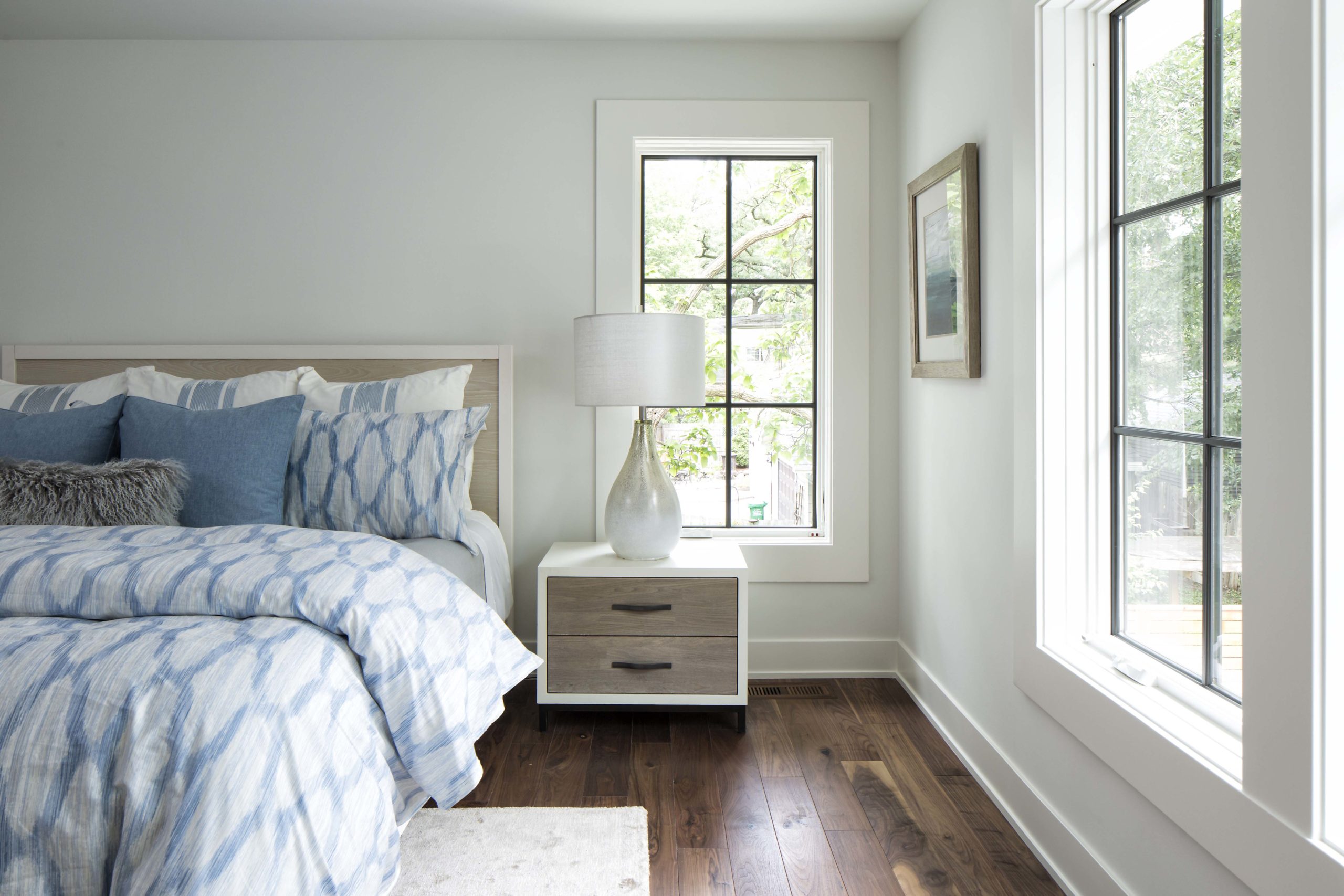 A blue and white bedroom with hardwood floors and a window.