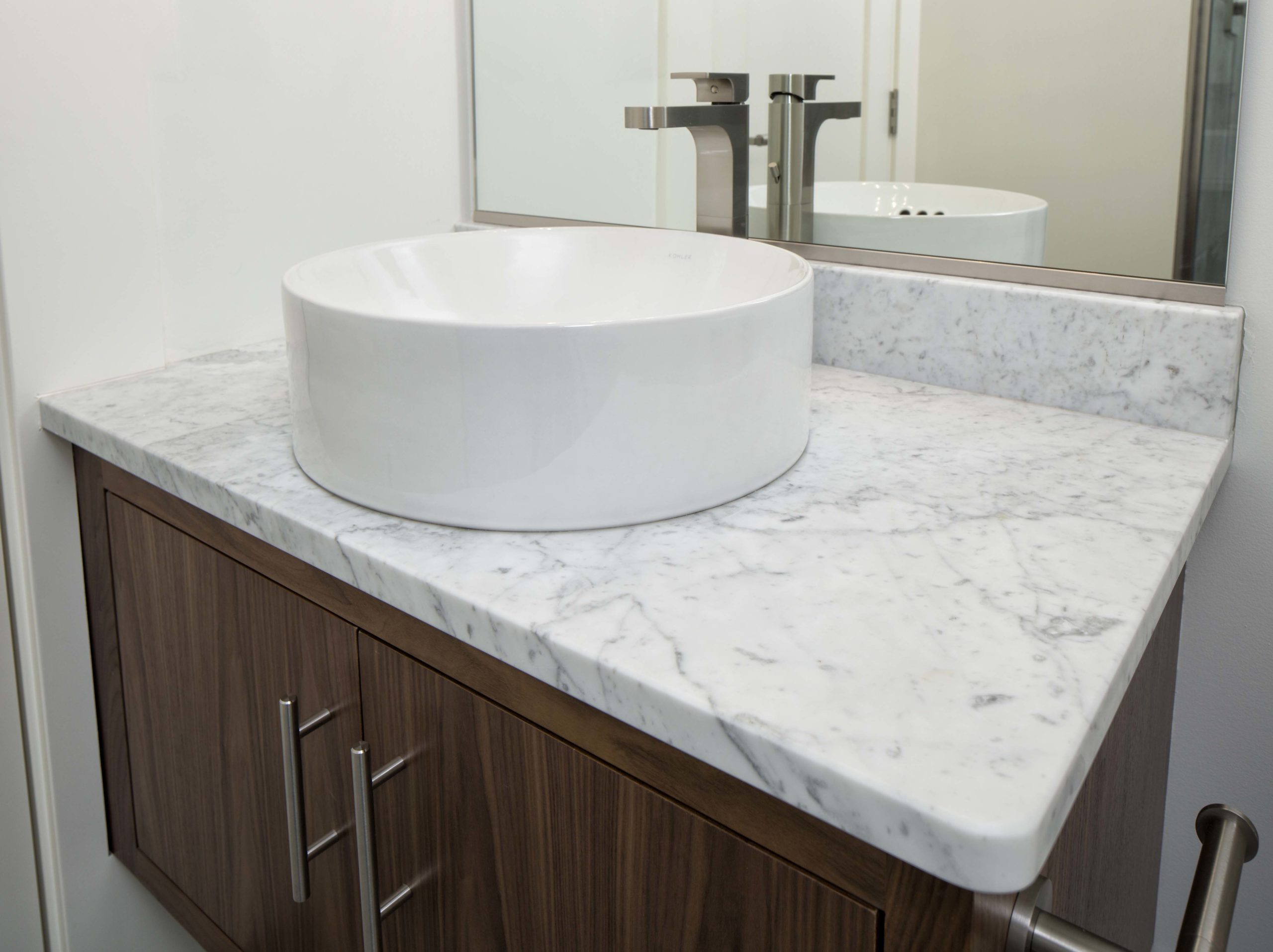 A bathroom with a white sink and marble counter top.