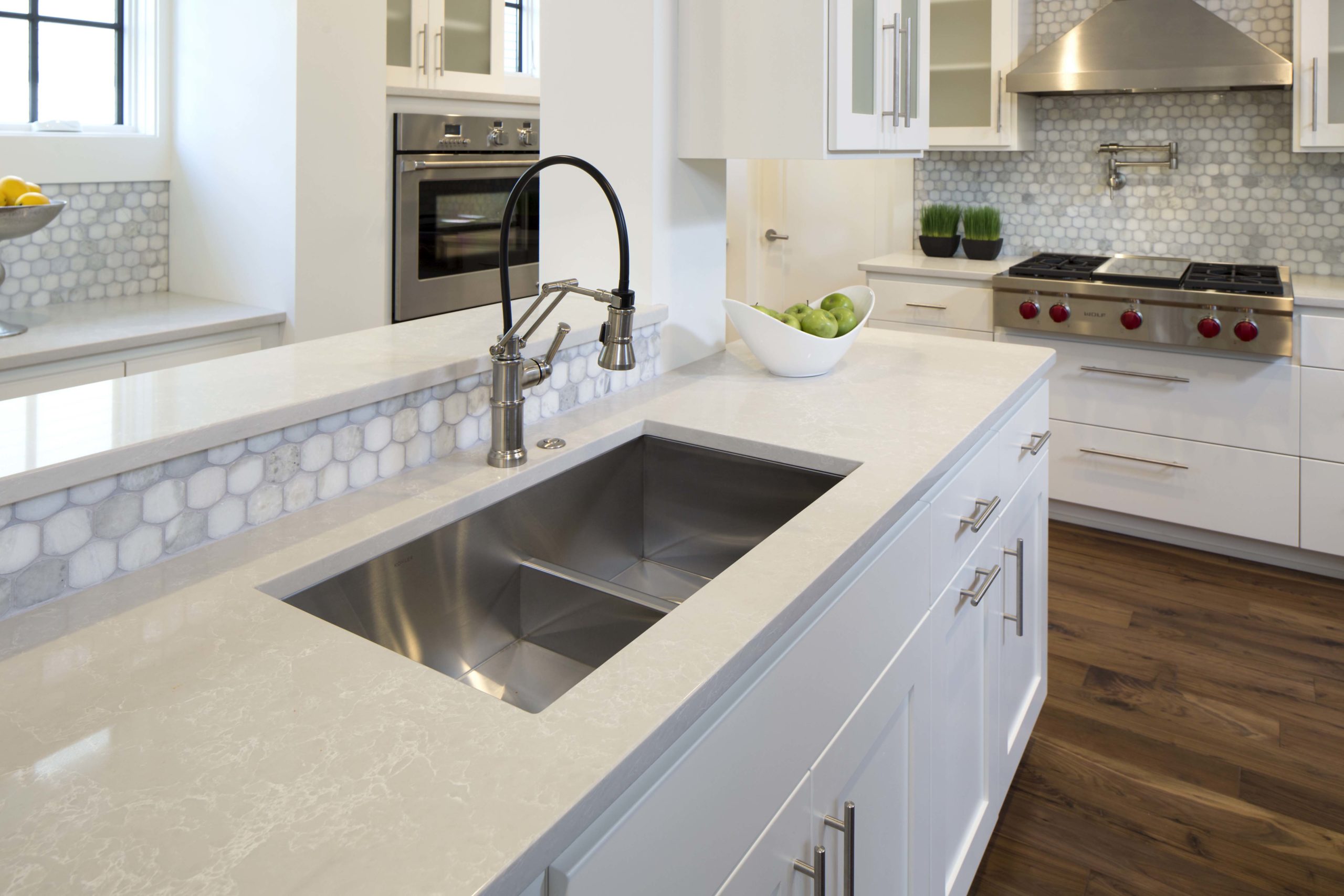 A white kitchen with a stainless steel sink.