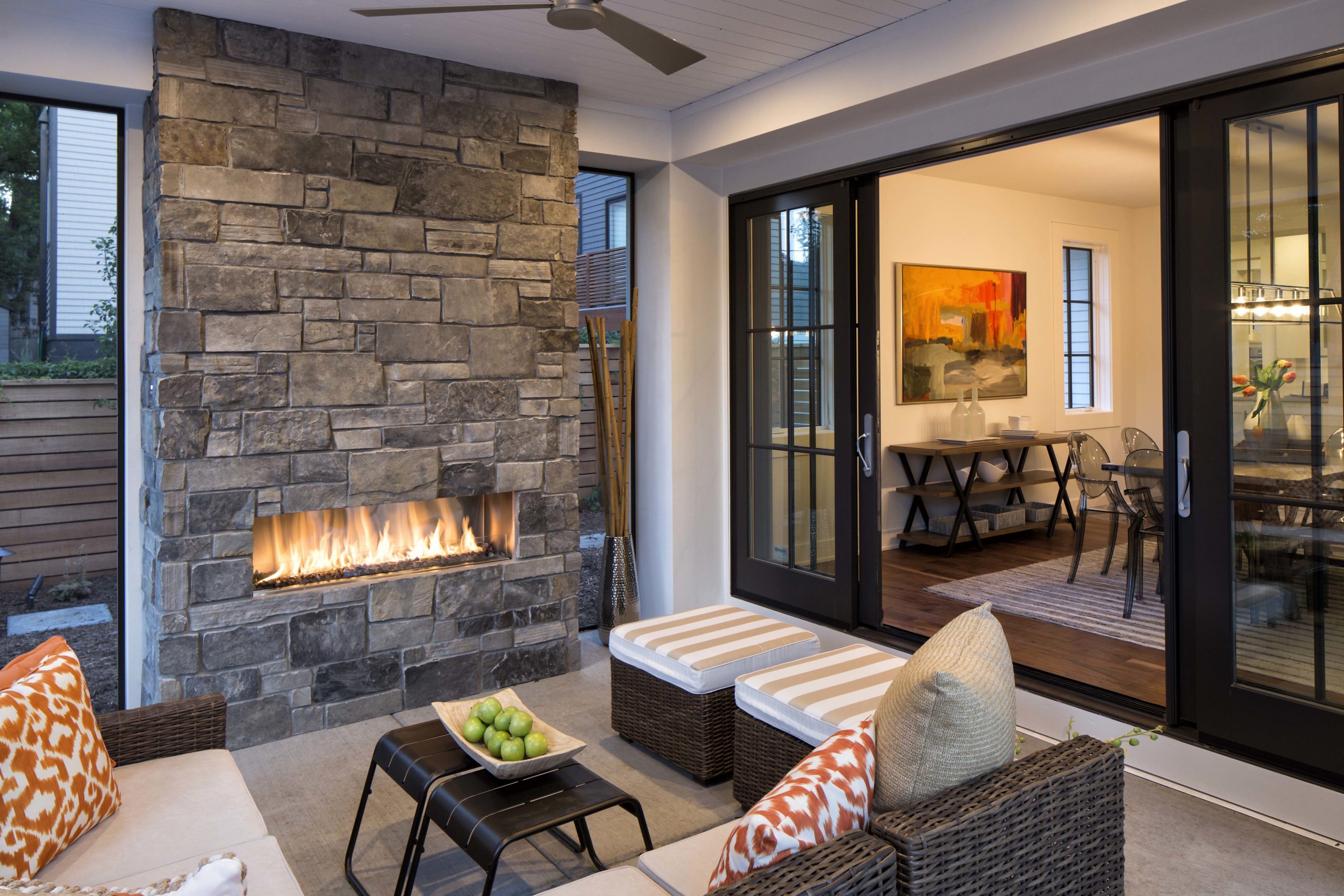 A living room with a stone fireplace and sliding glass doors.