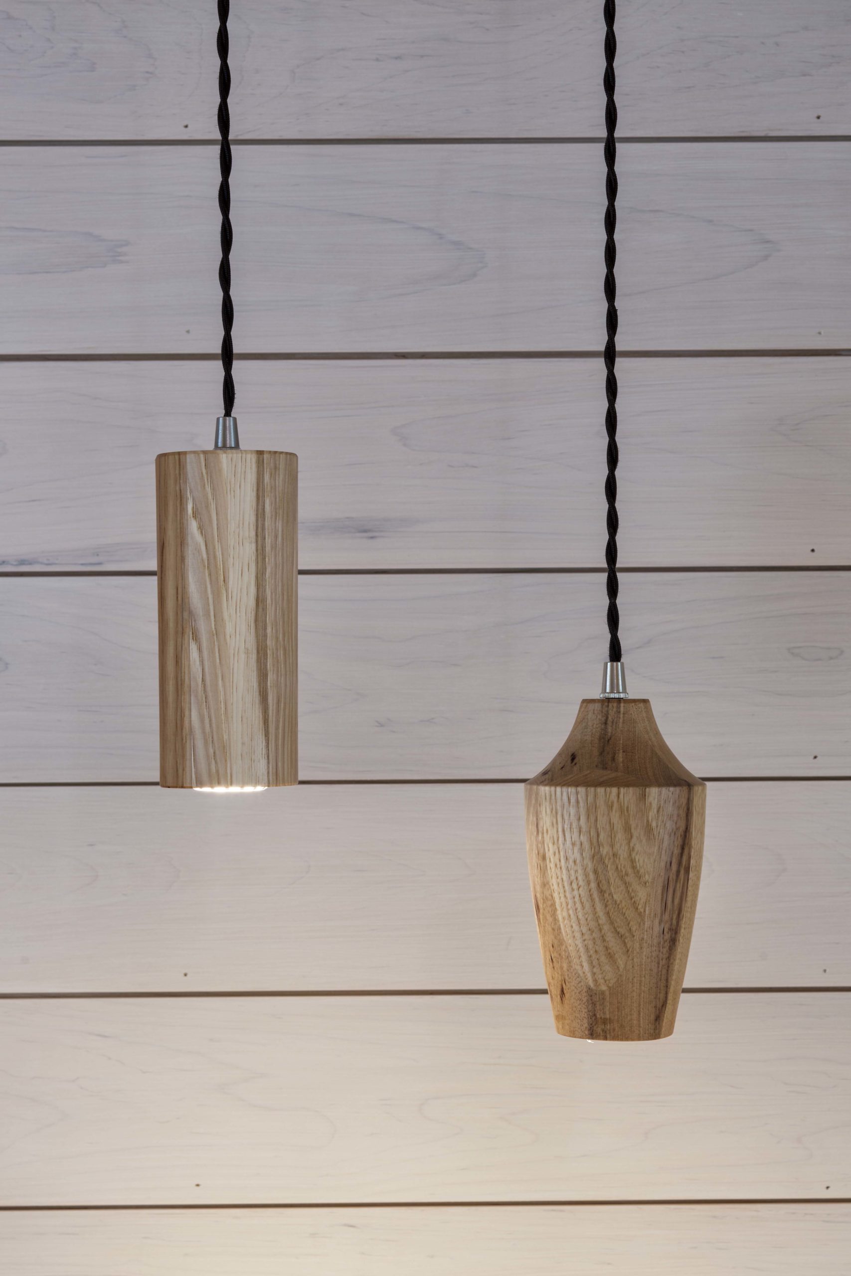 Two wooden pendant lights hanging from a wooden wall.