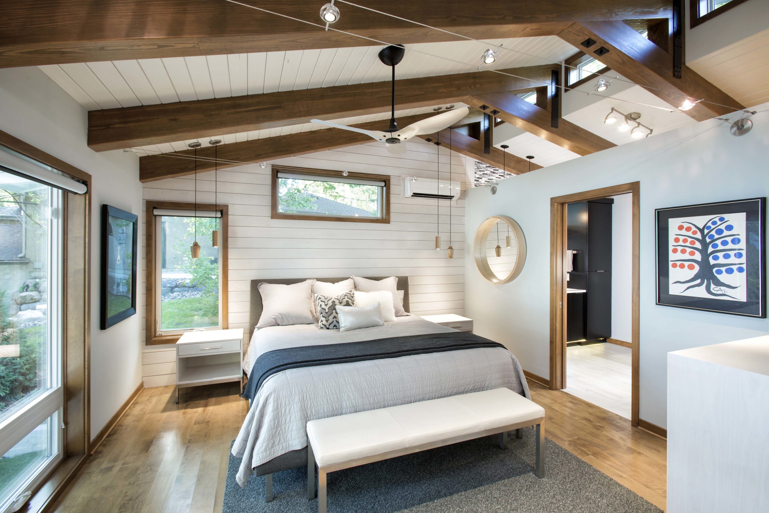 A bedroom with wooden beams and a ceiling fan.
