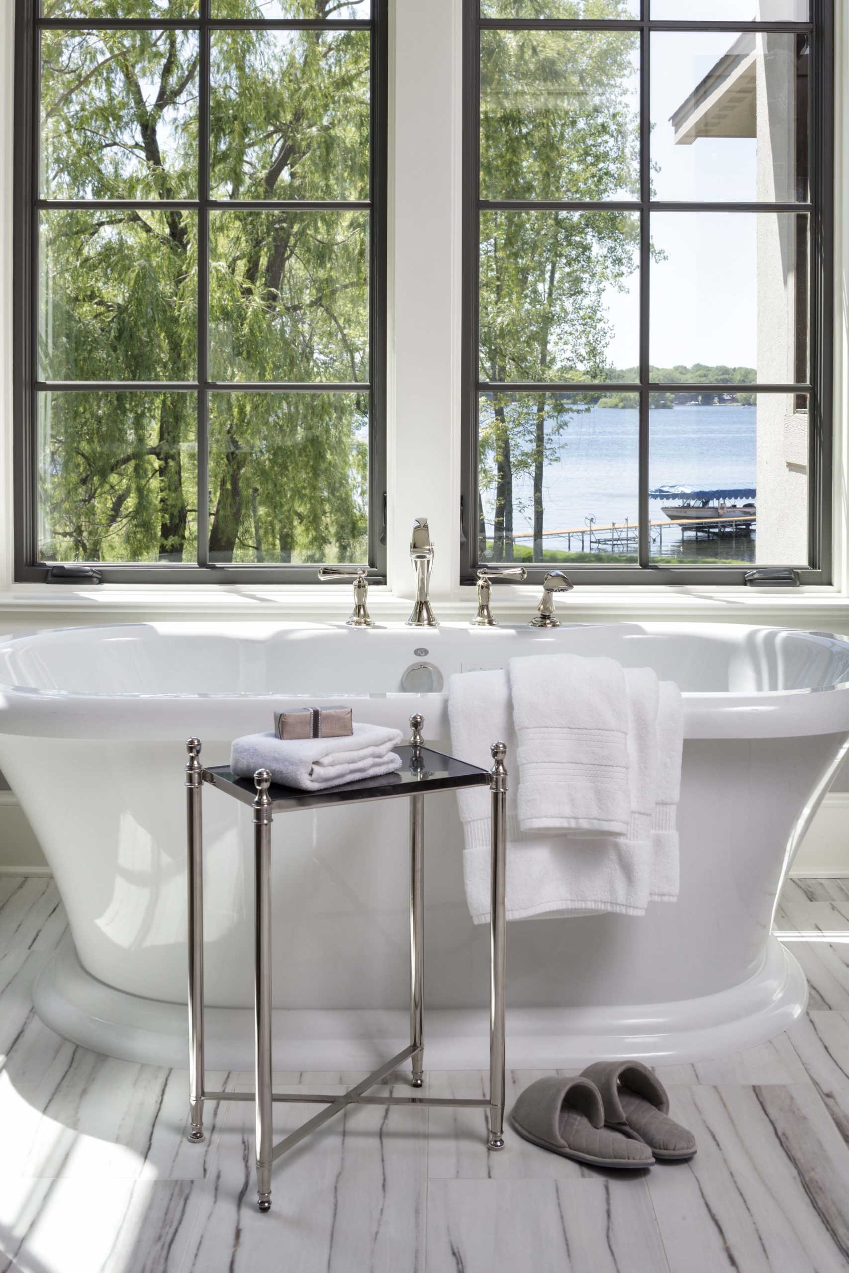 A white bathroom with a large window overlooking a lake.