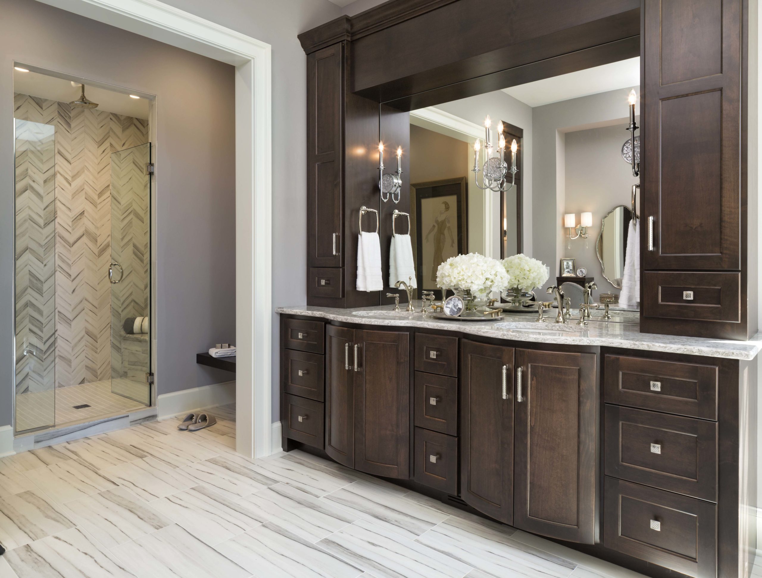 A bathroom with dark wood cabinets and marble counter tops.