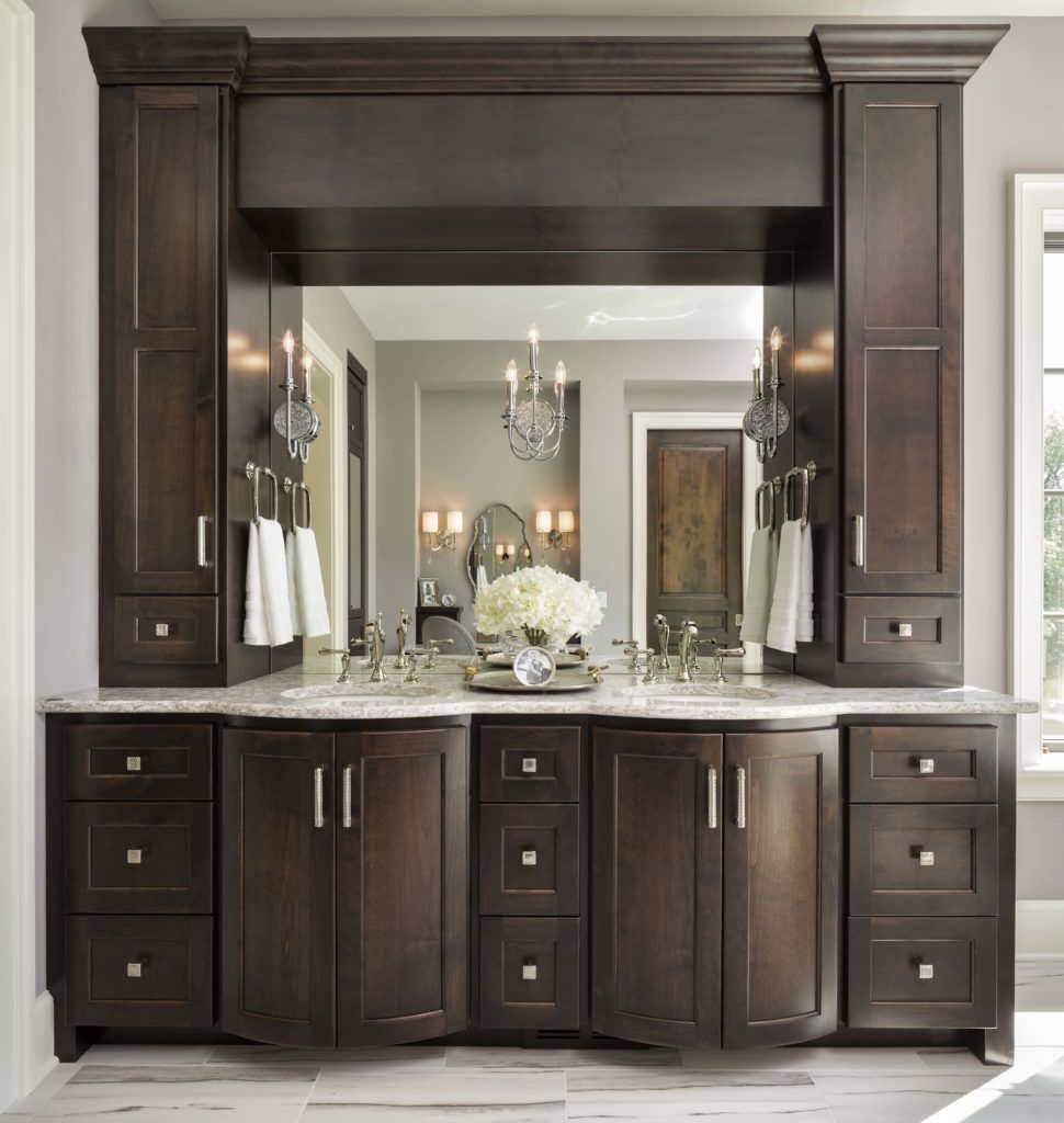 A bathroom with dark wood cabinets and marble counter tops.