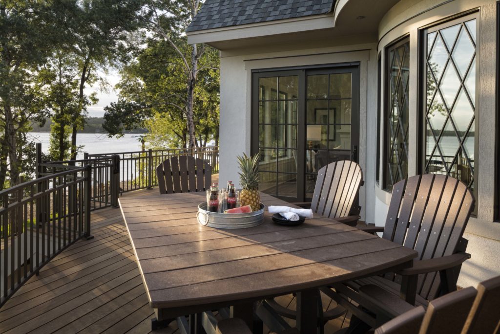 A deck with a table and chairs overlooking a lake.