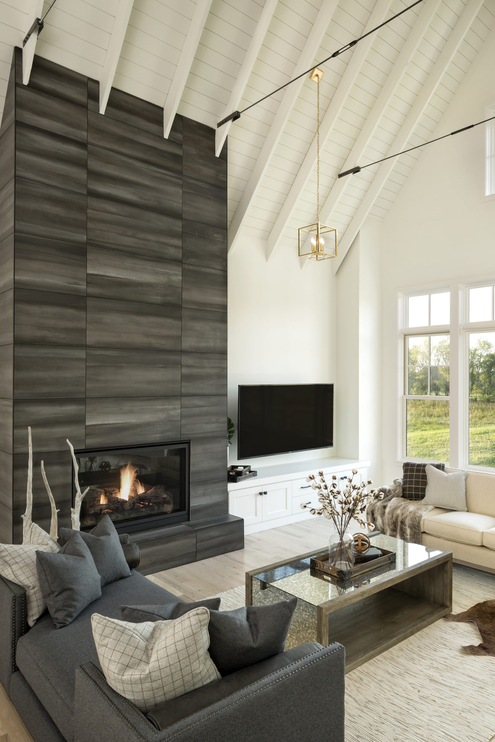 A modern living room with a fireplace and wood beams.