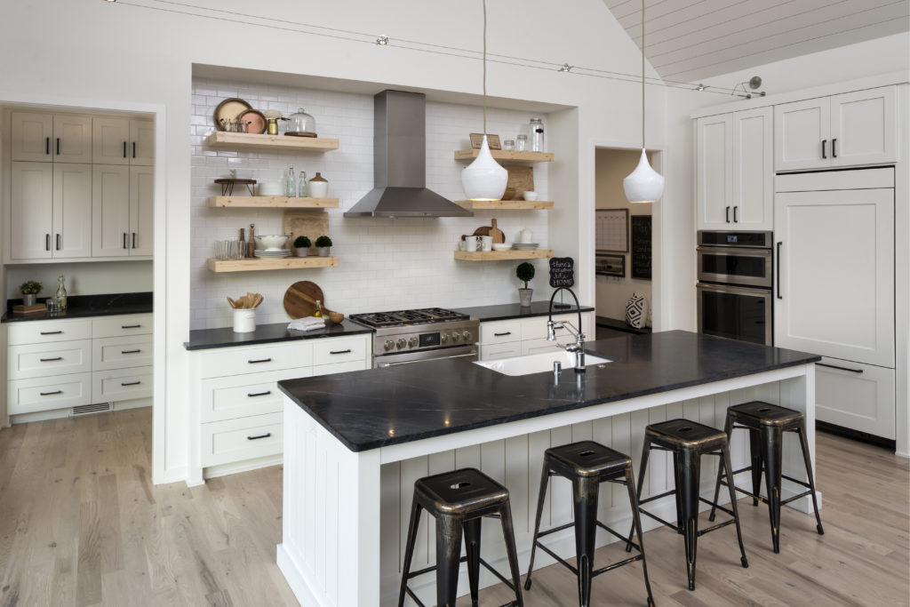A white kitchen with black counter tops and stools.