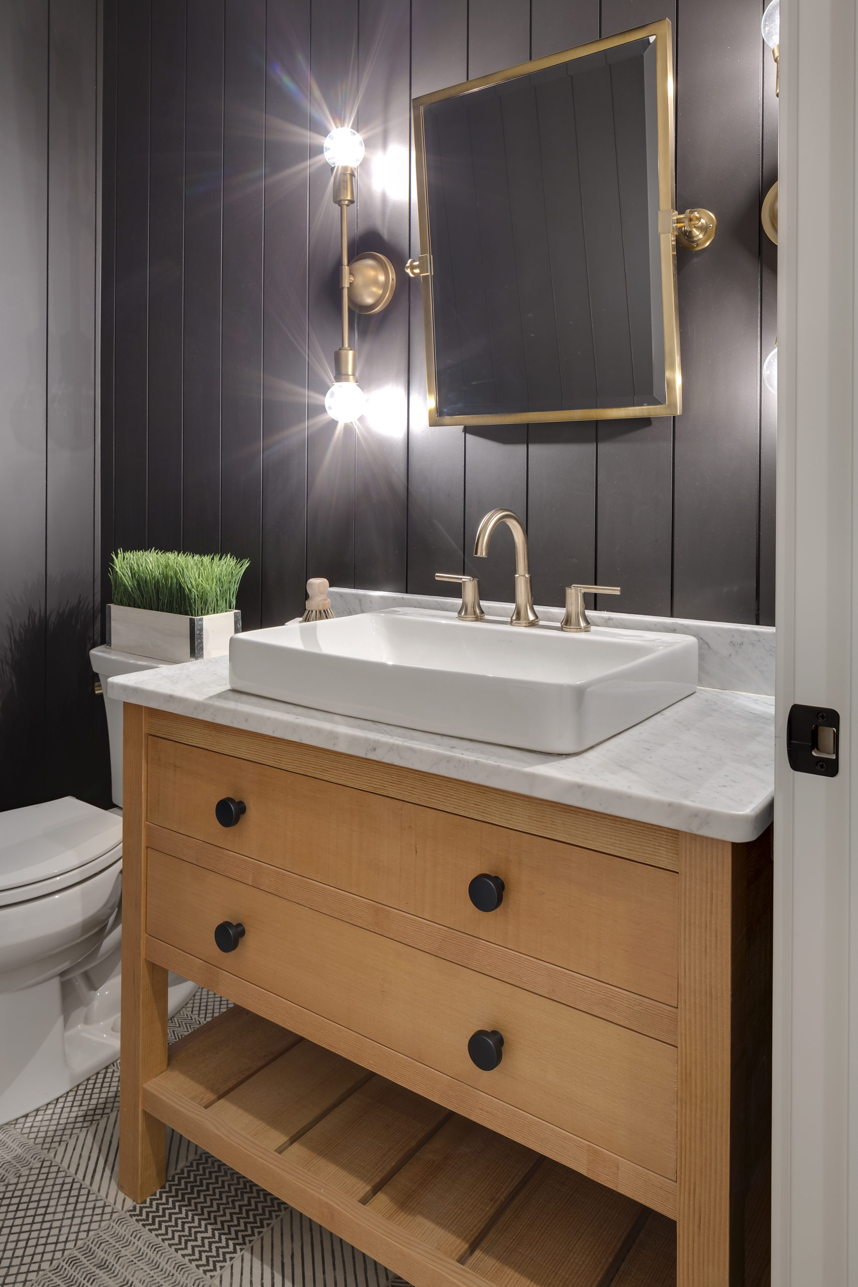 A bathroom with black walls and wood paneling.