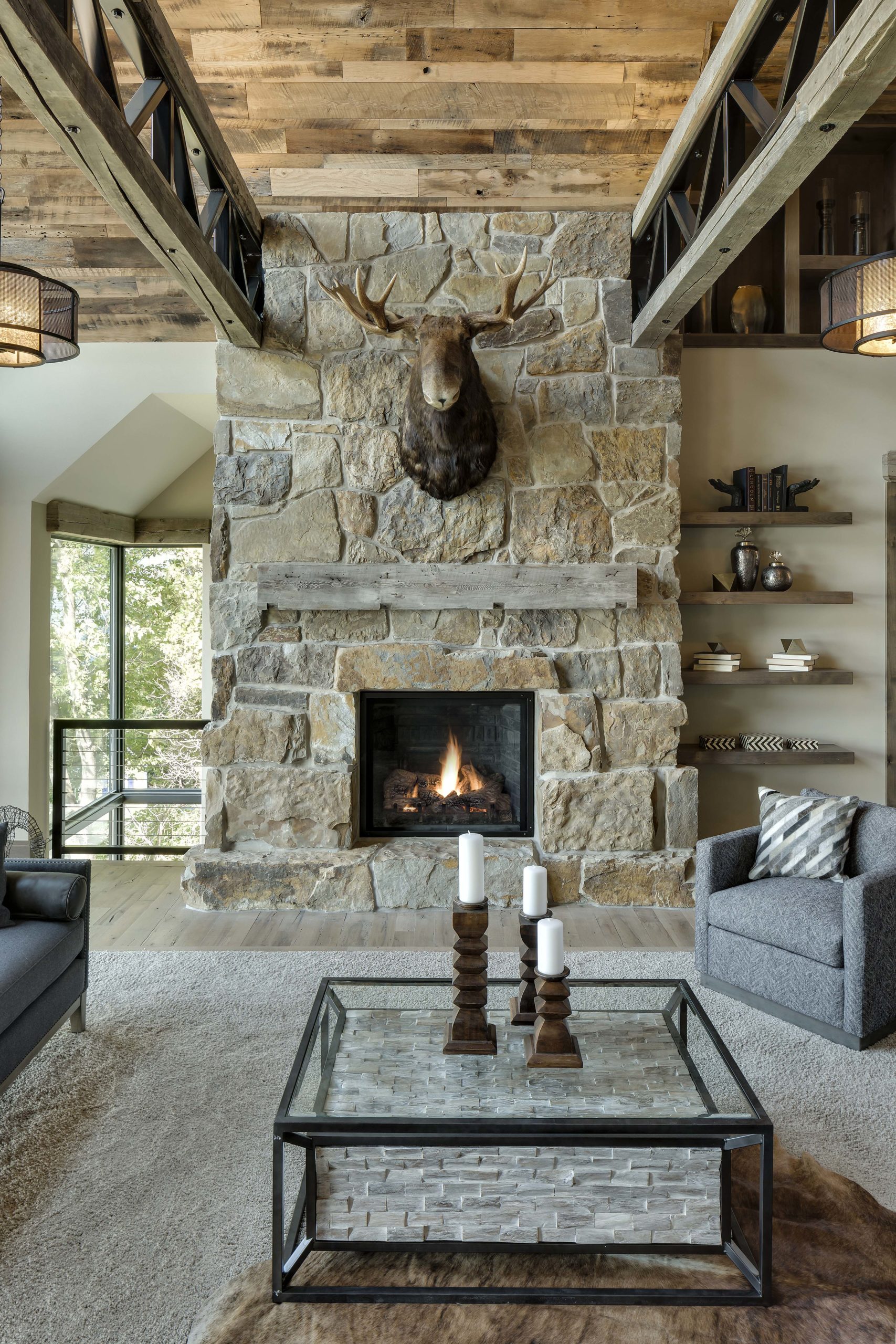 A living room with a stone fireplace and a deer head.