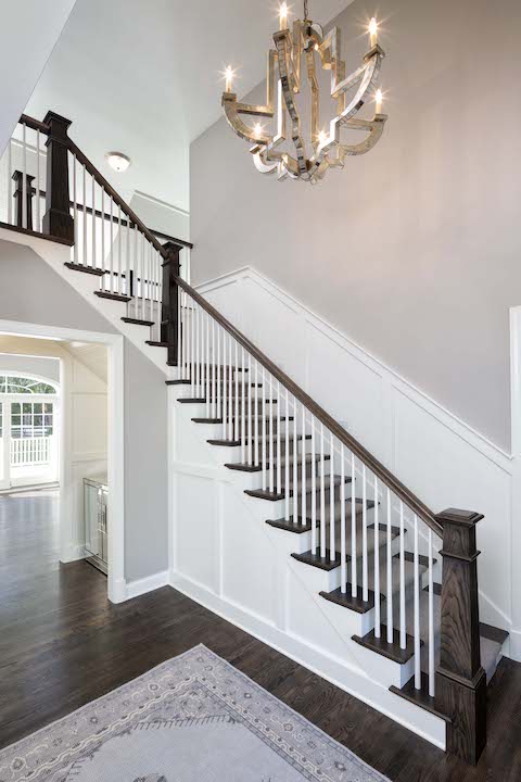 A staircase in a home with hardwood floors and a chandelier.