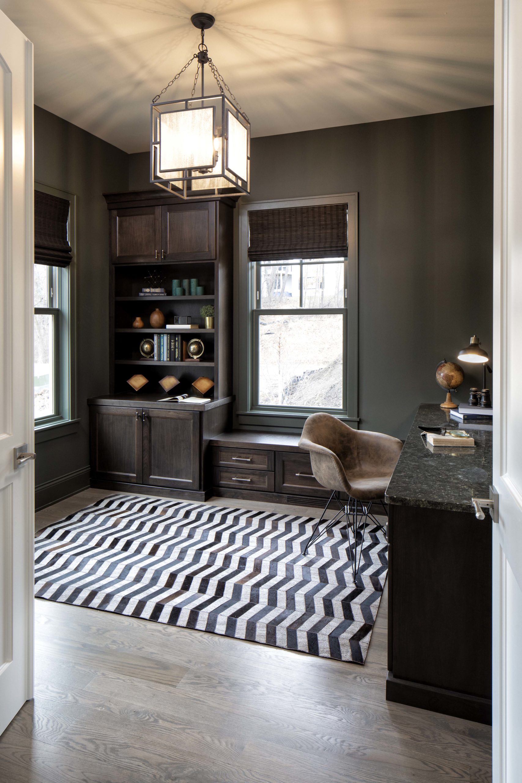 A home office with black walls and a striped rug.