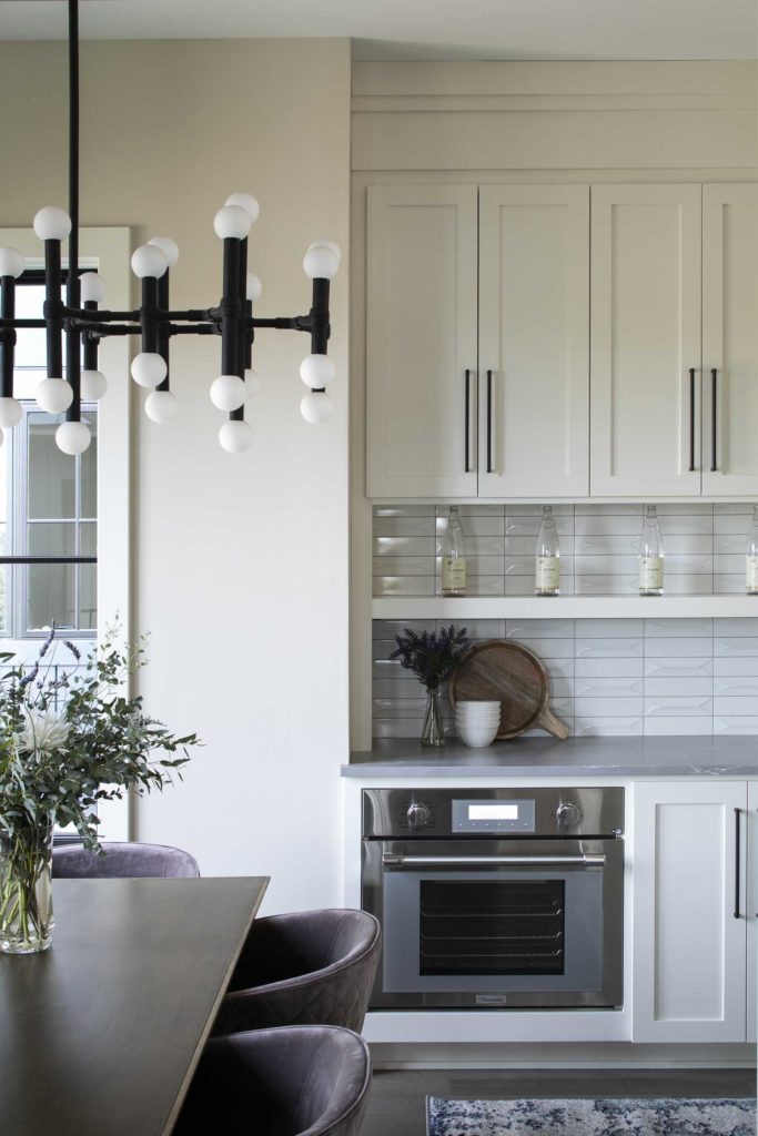 A white kitchen with gray cabinets and a chandelier.