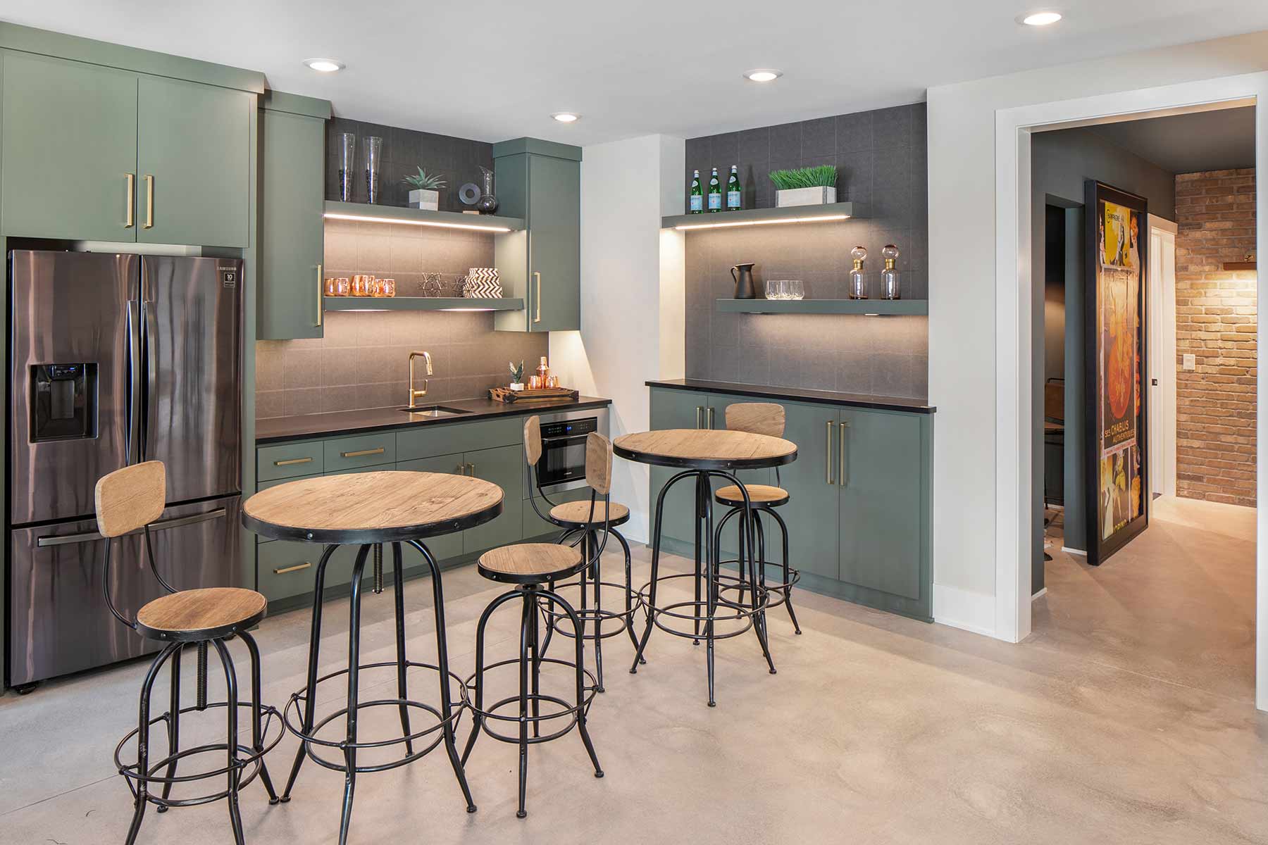 A kitchen with green cabinets and bar stools.