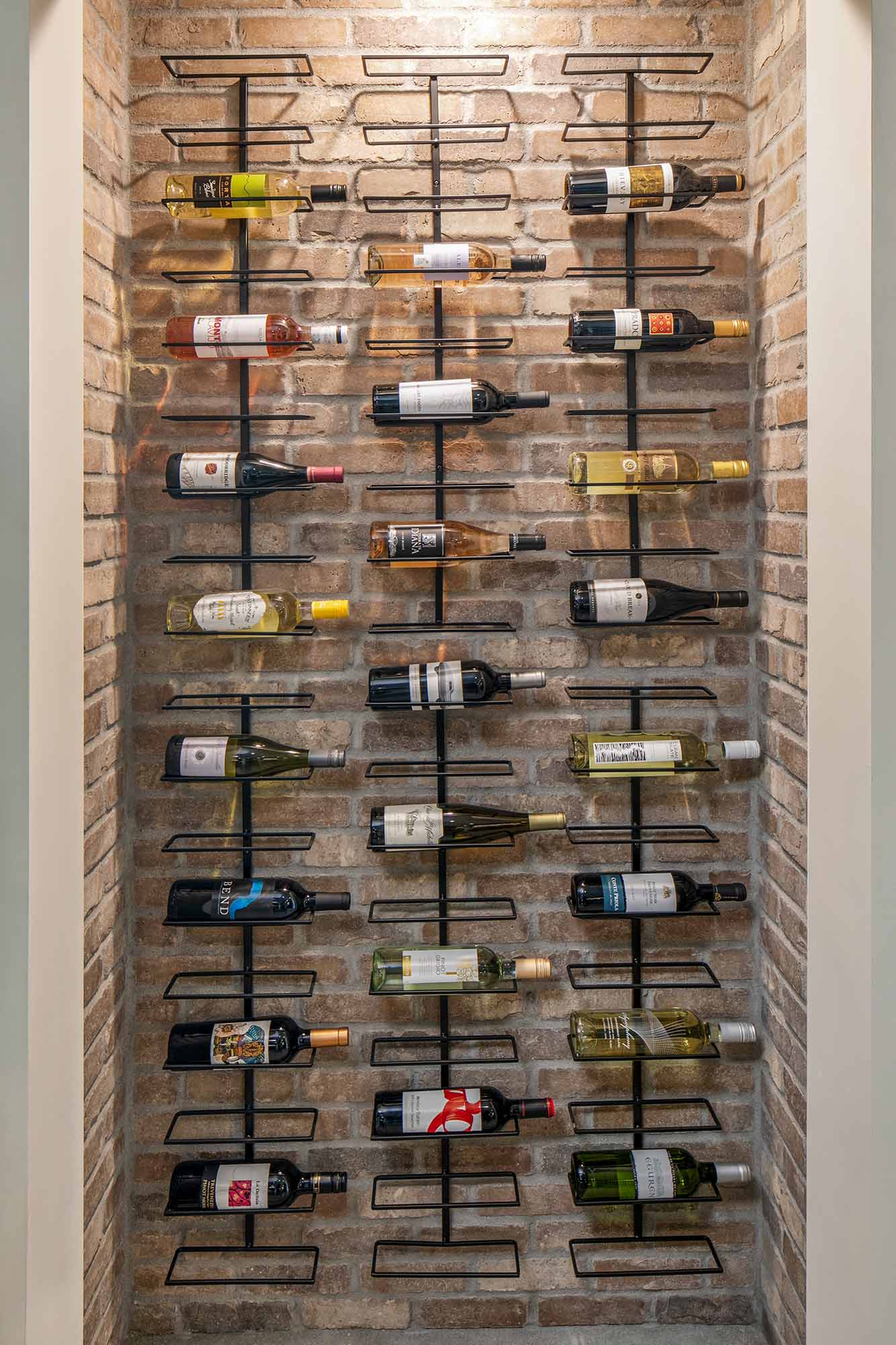 A wall mounted wine rack with many bottles of wine.