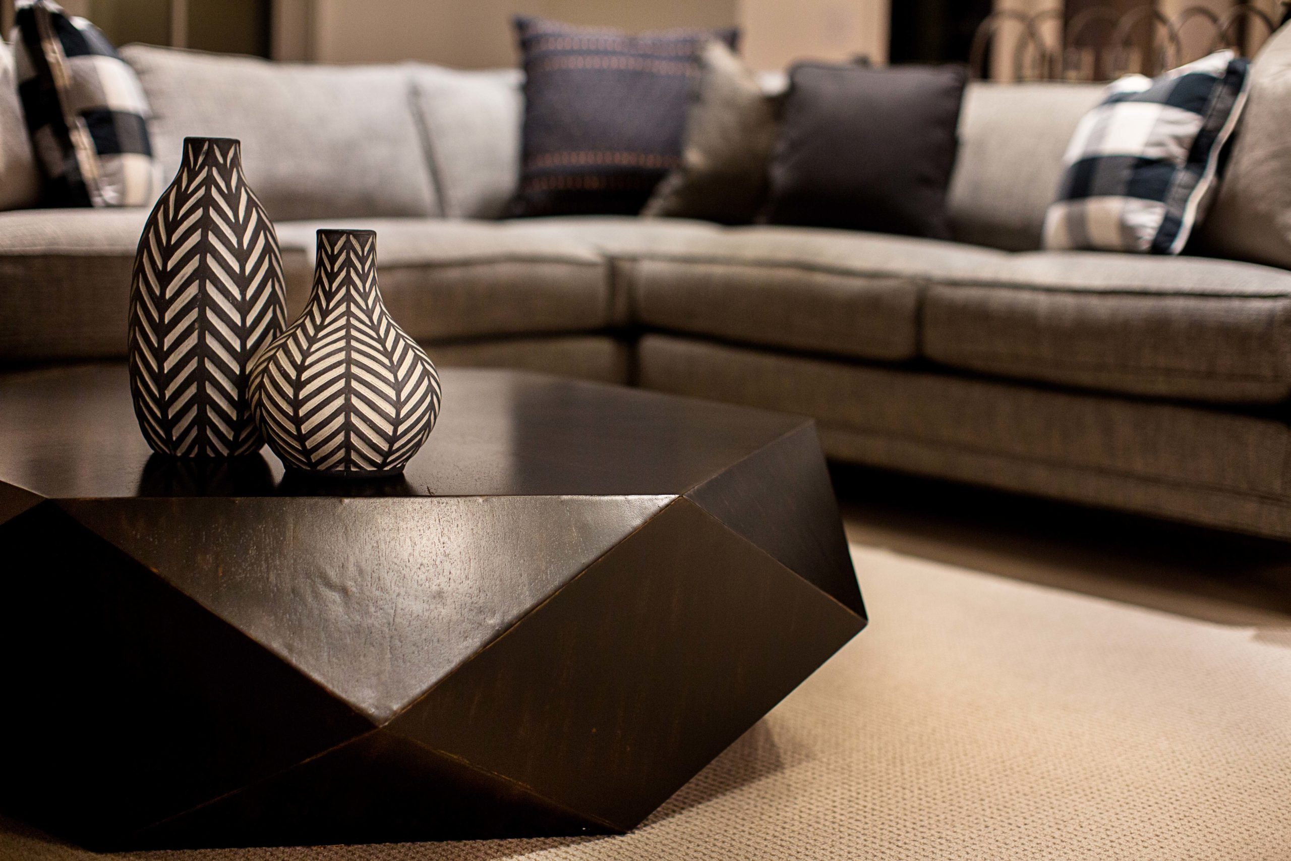 Abstract brown coffee table with 2 decorative vases by sectional couch.