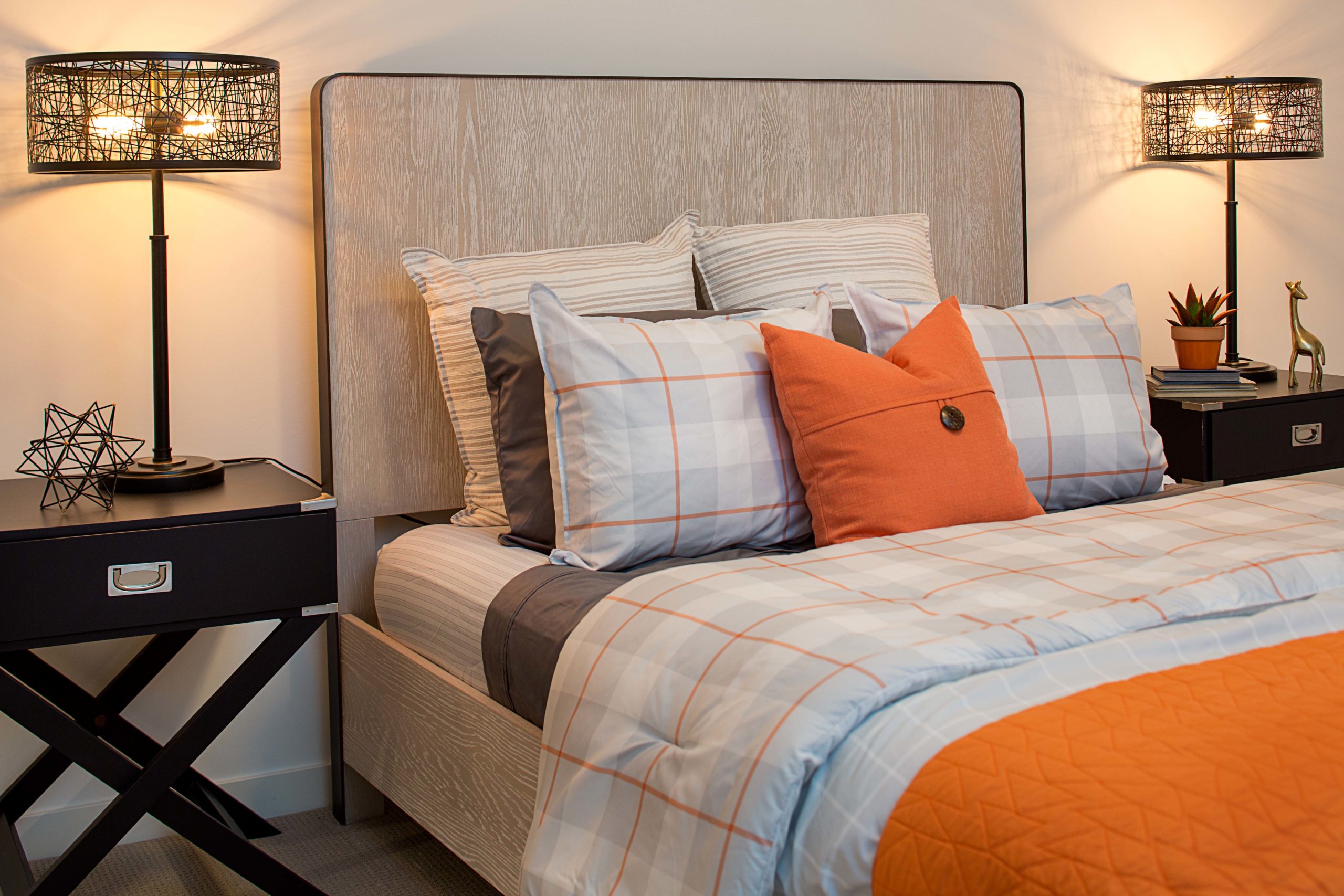 A bed with an orange and gray comforter.