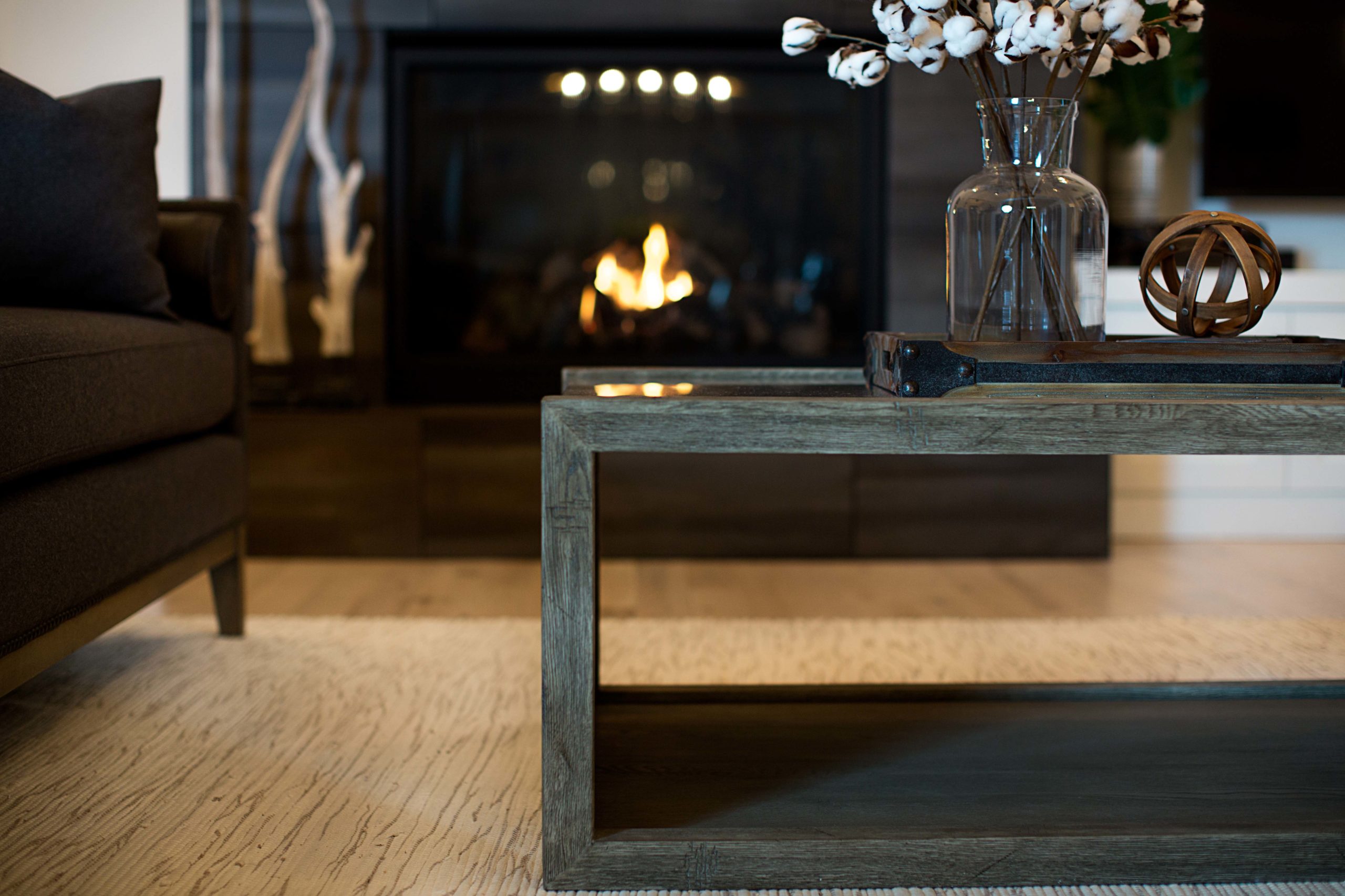 Dark wood coffee table with unique accessories near fireplace.