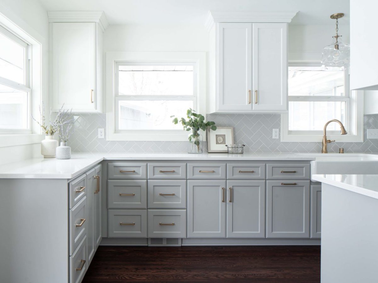 A white kitchen with gray cabinets and hardwood floors.