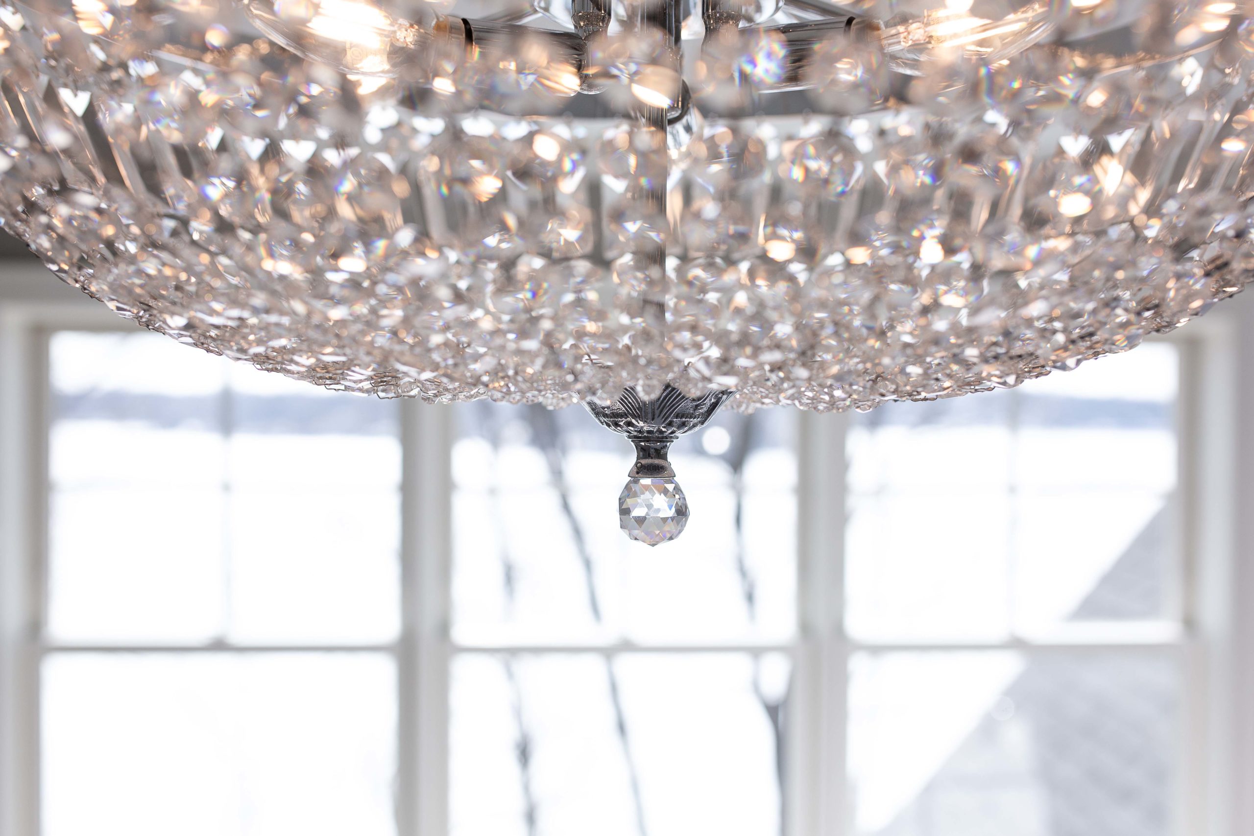 A large crystal chandelier hangs above a window.
