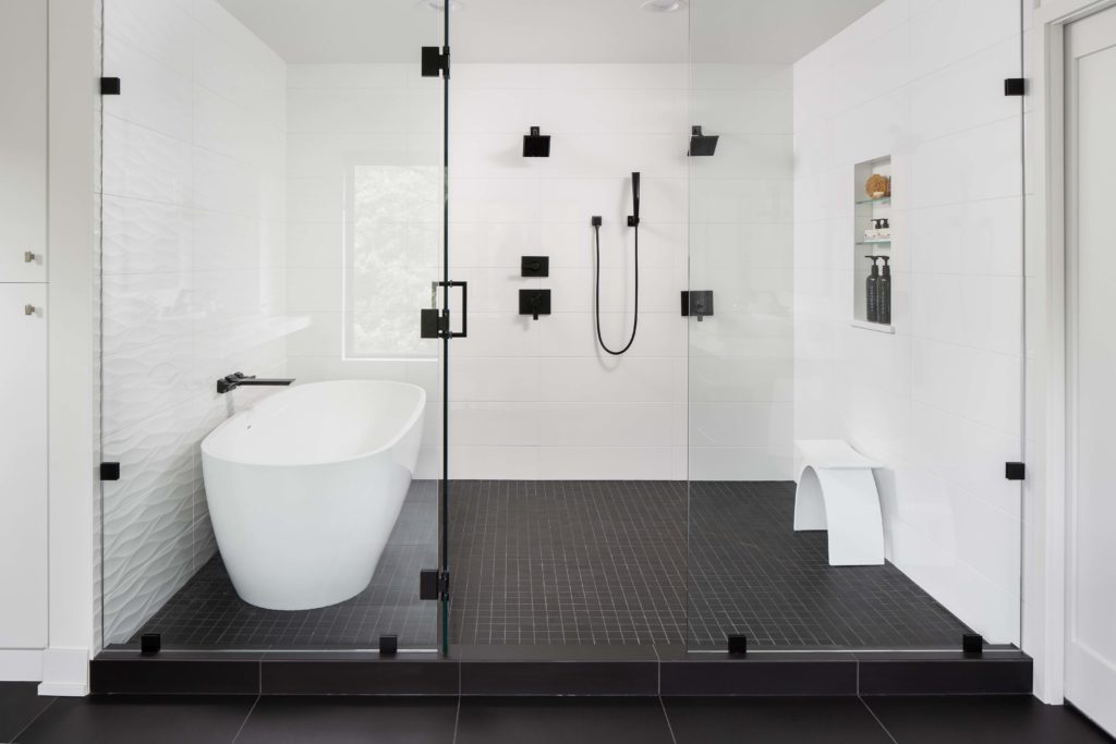 A black and white bathroom with glass shower doors.
