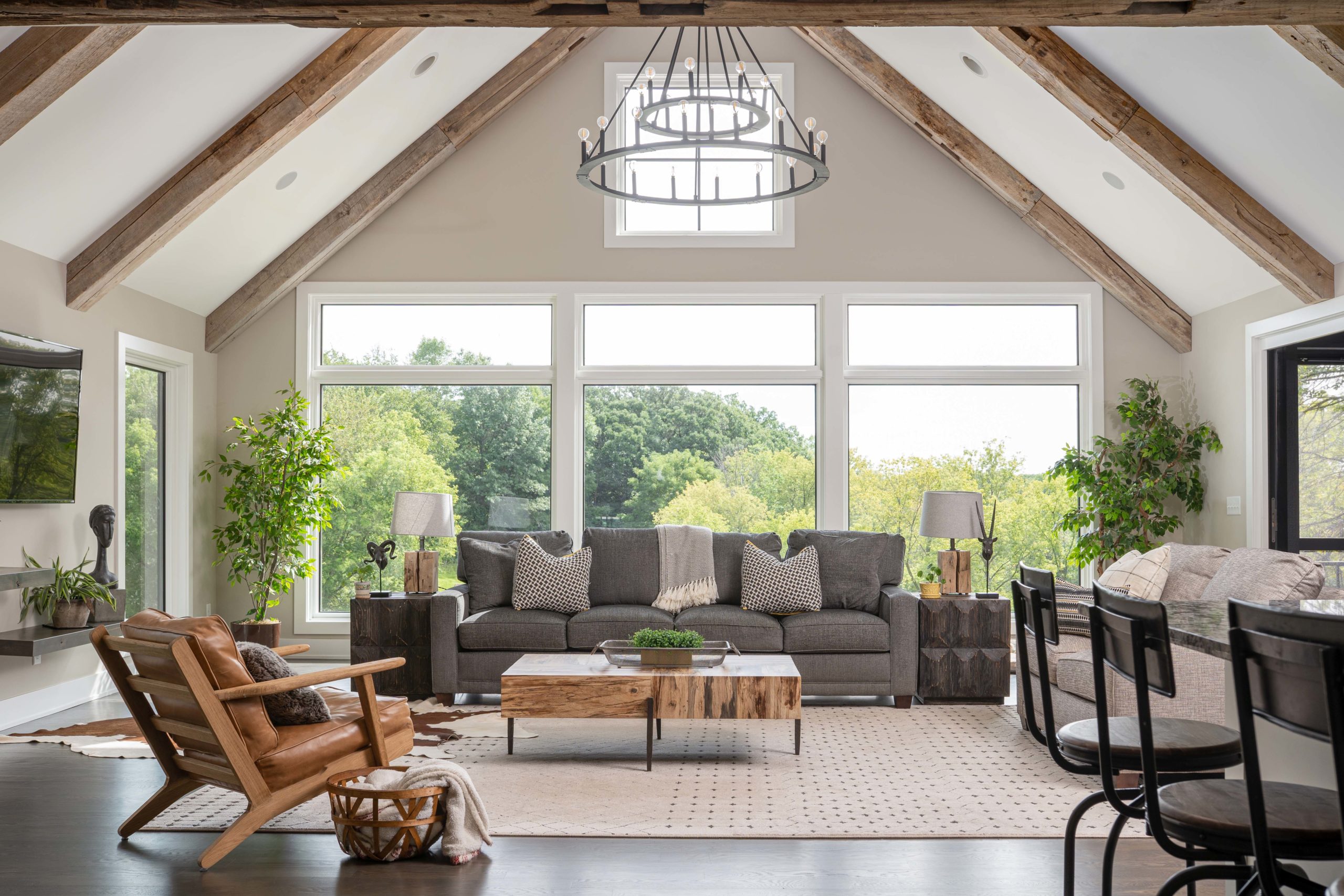 A living room with large windows and wood beams.