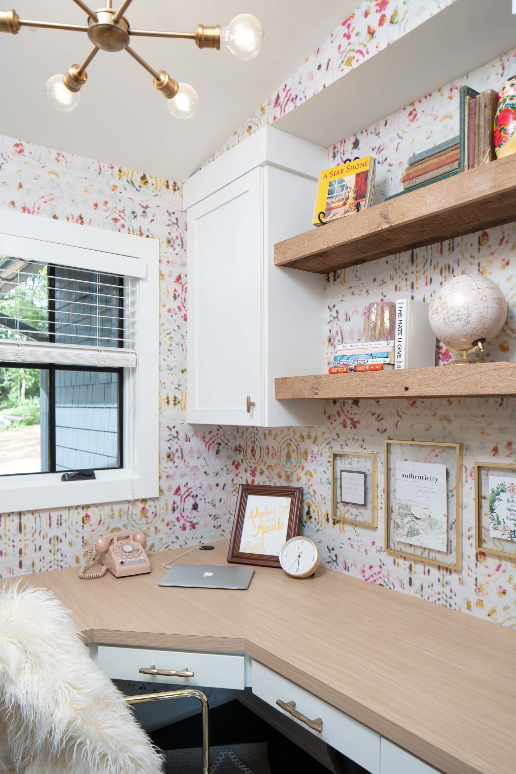 A home office with floral wallpaper and a furry chair.