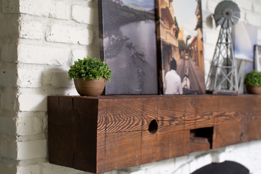 A wooden mantle with pictures hanging on it.
