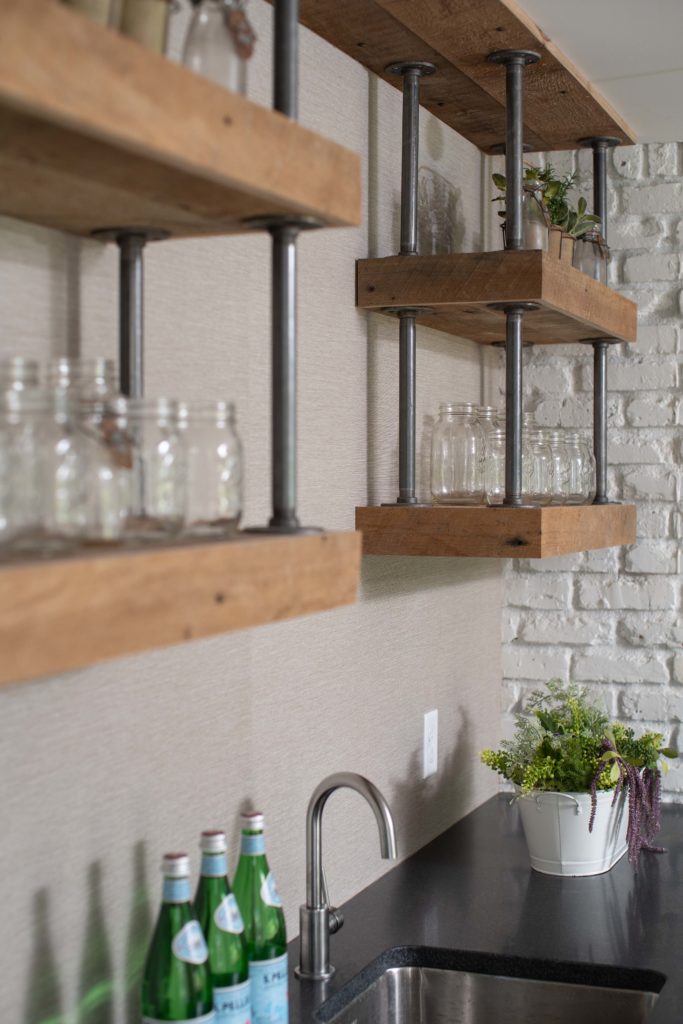 A kitchen with wooden shelves and a sink.
