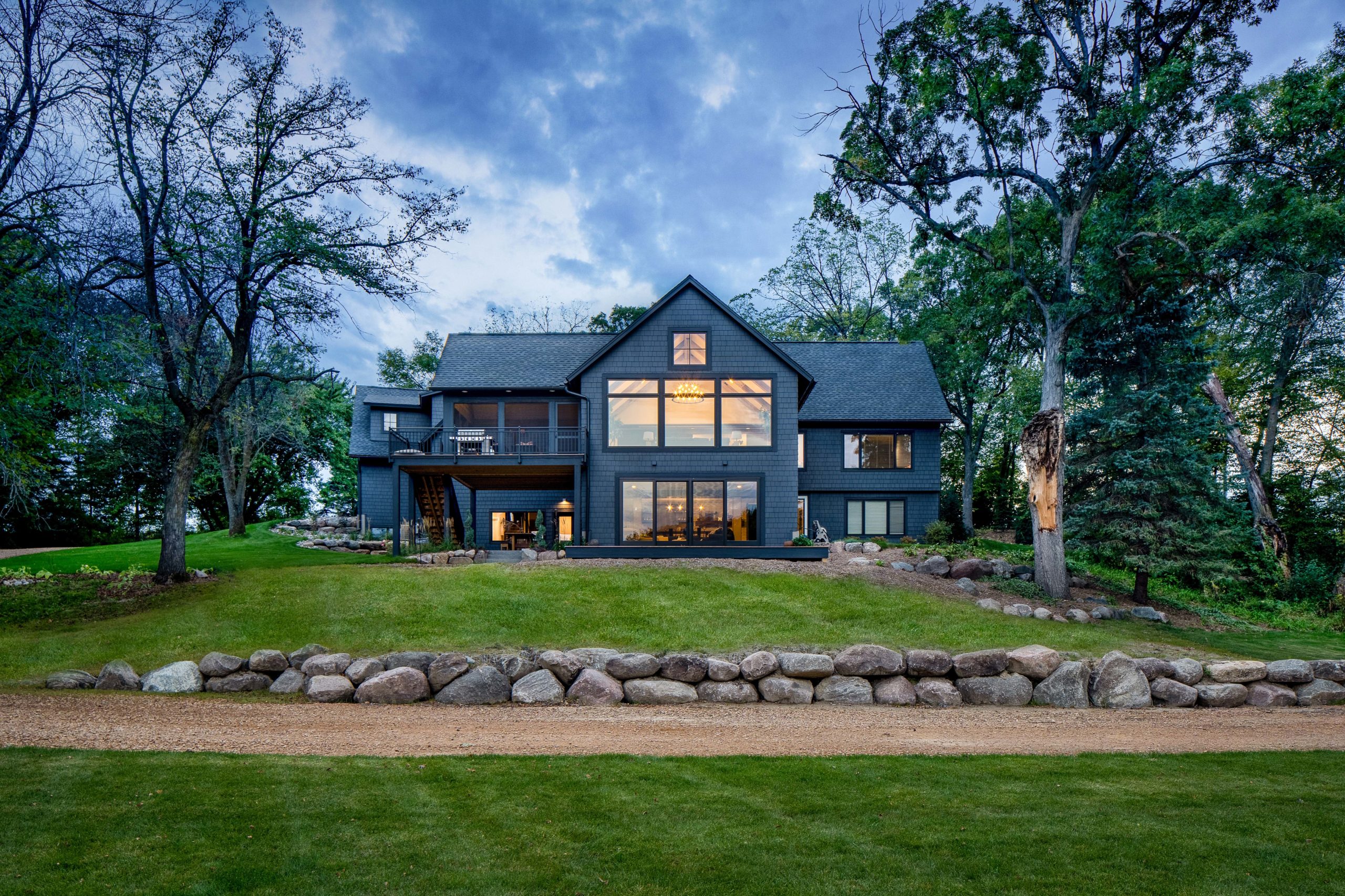 A black home with a large rock in front of it.
