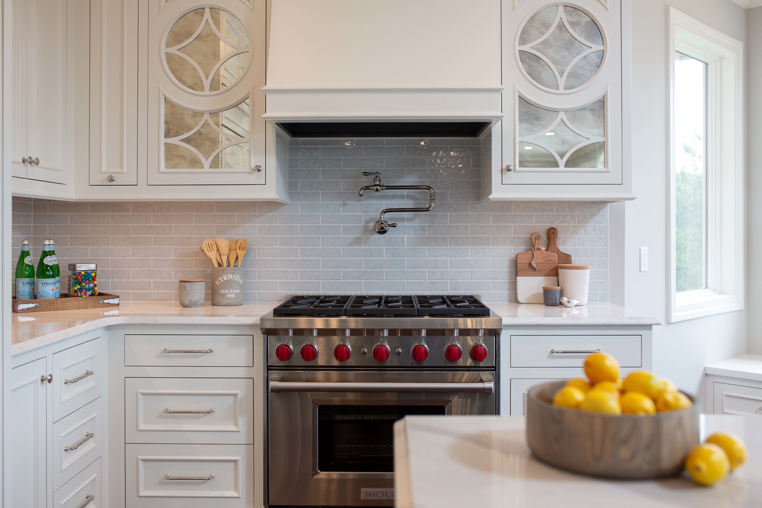 A white kitchen with a stove and lemons.