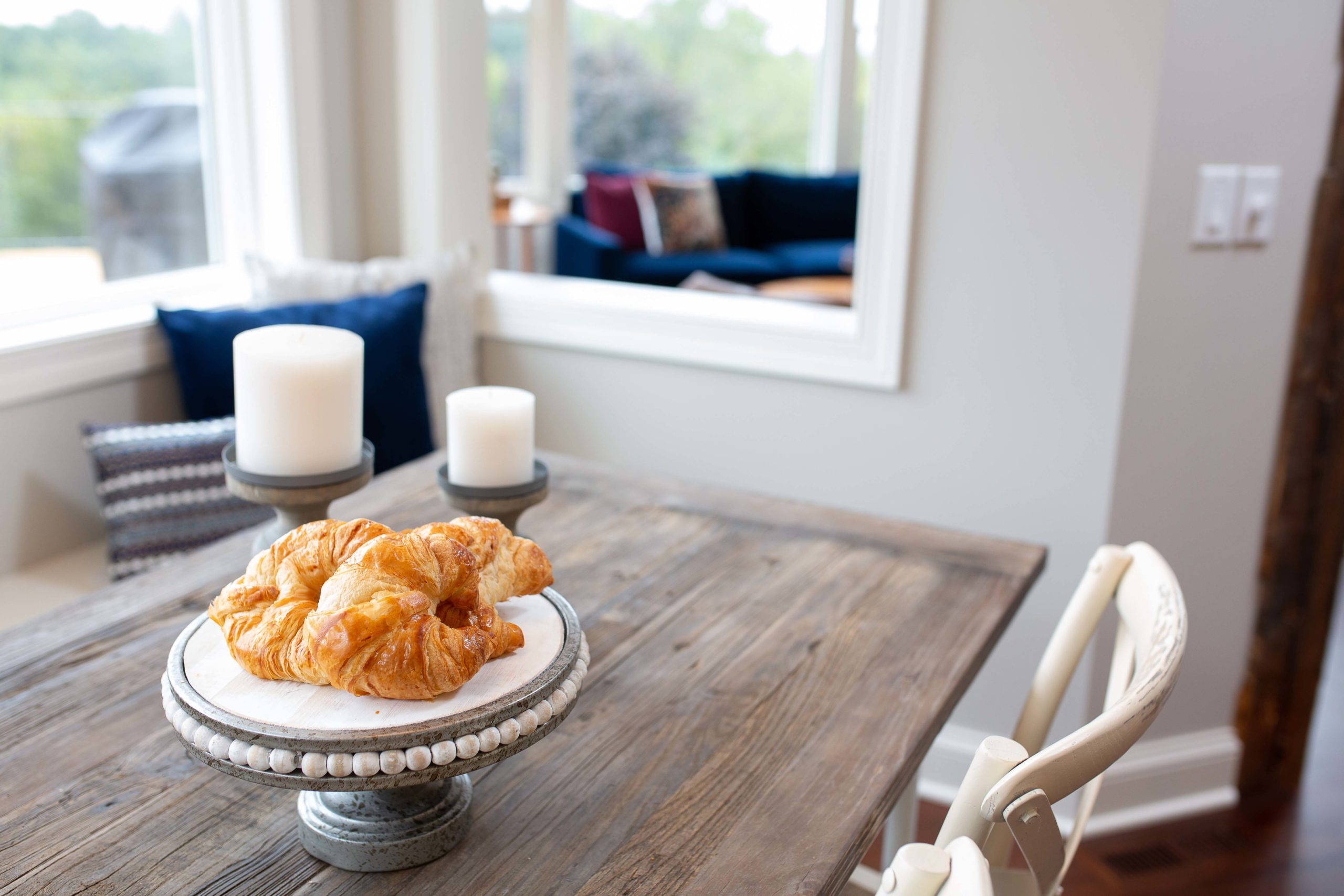 A plate of croissants on a table in front of a window.