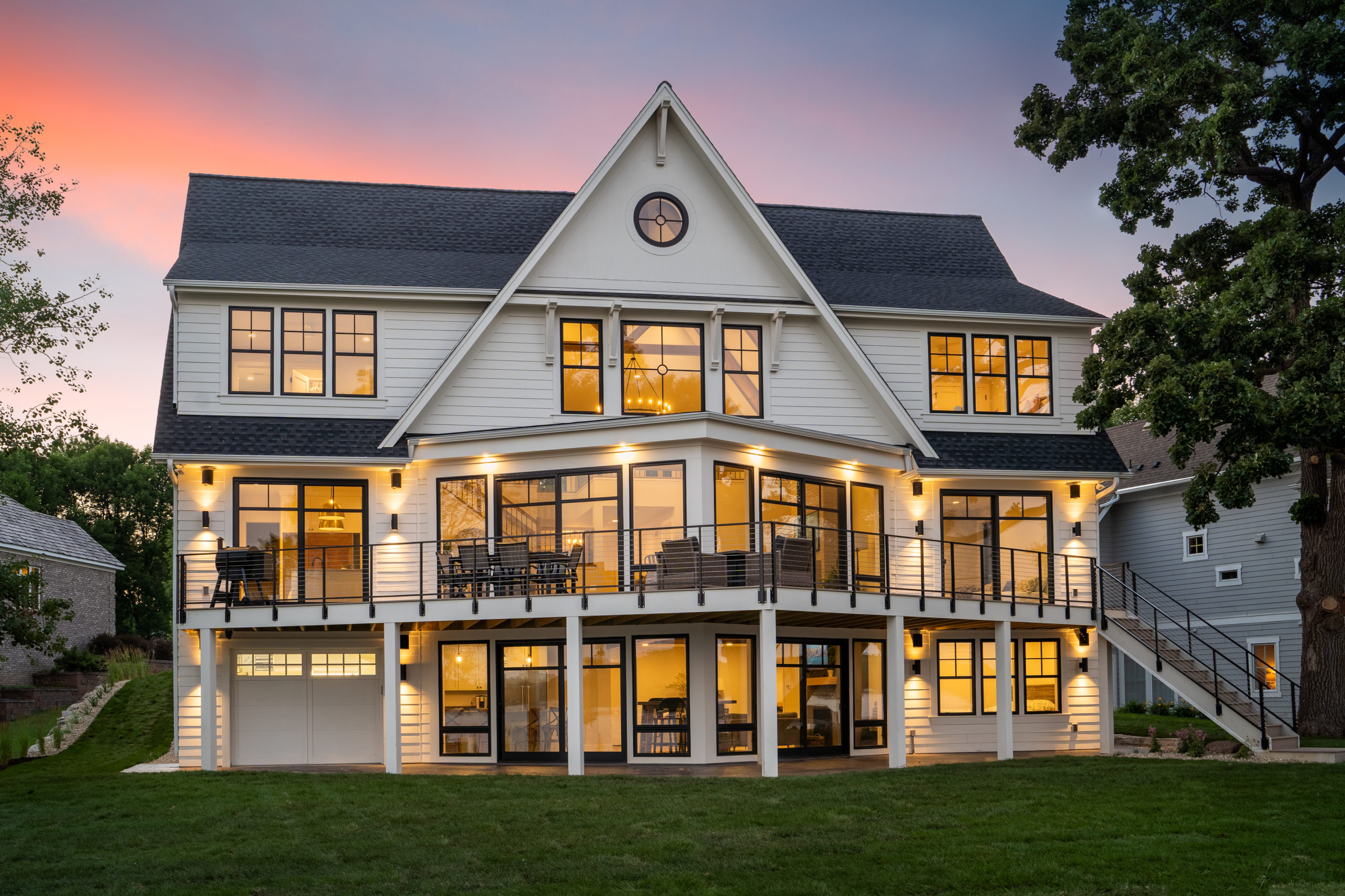 A large white house with a spacious deck at dusk, perfect for home exterior design ideas.