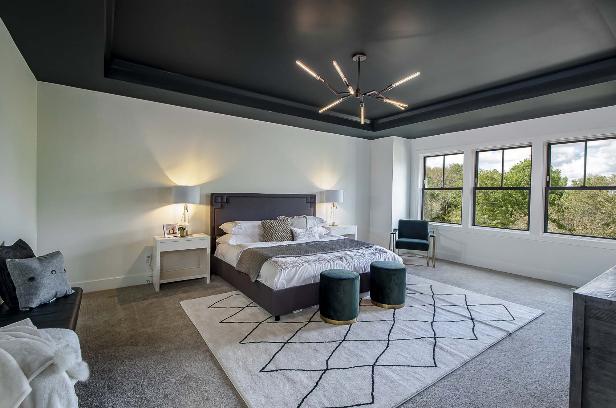Large master bedroom with white walls, white trim and black ceiling with contemporary light fixture.