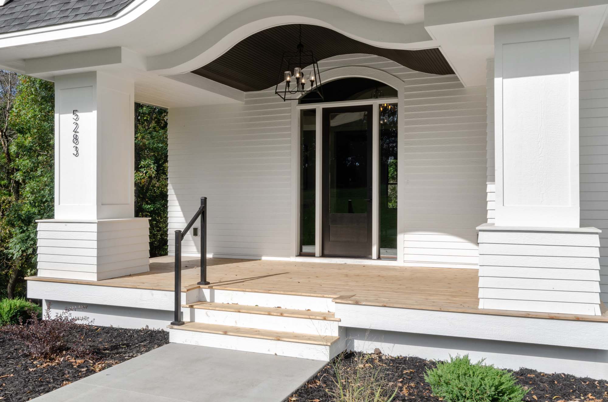 Home exterior design ideas: A stunning white house featuring a porch and steps.