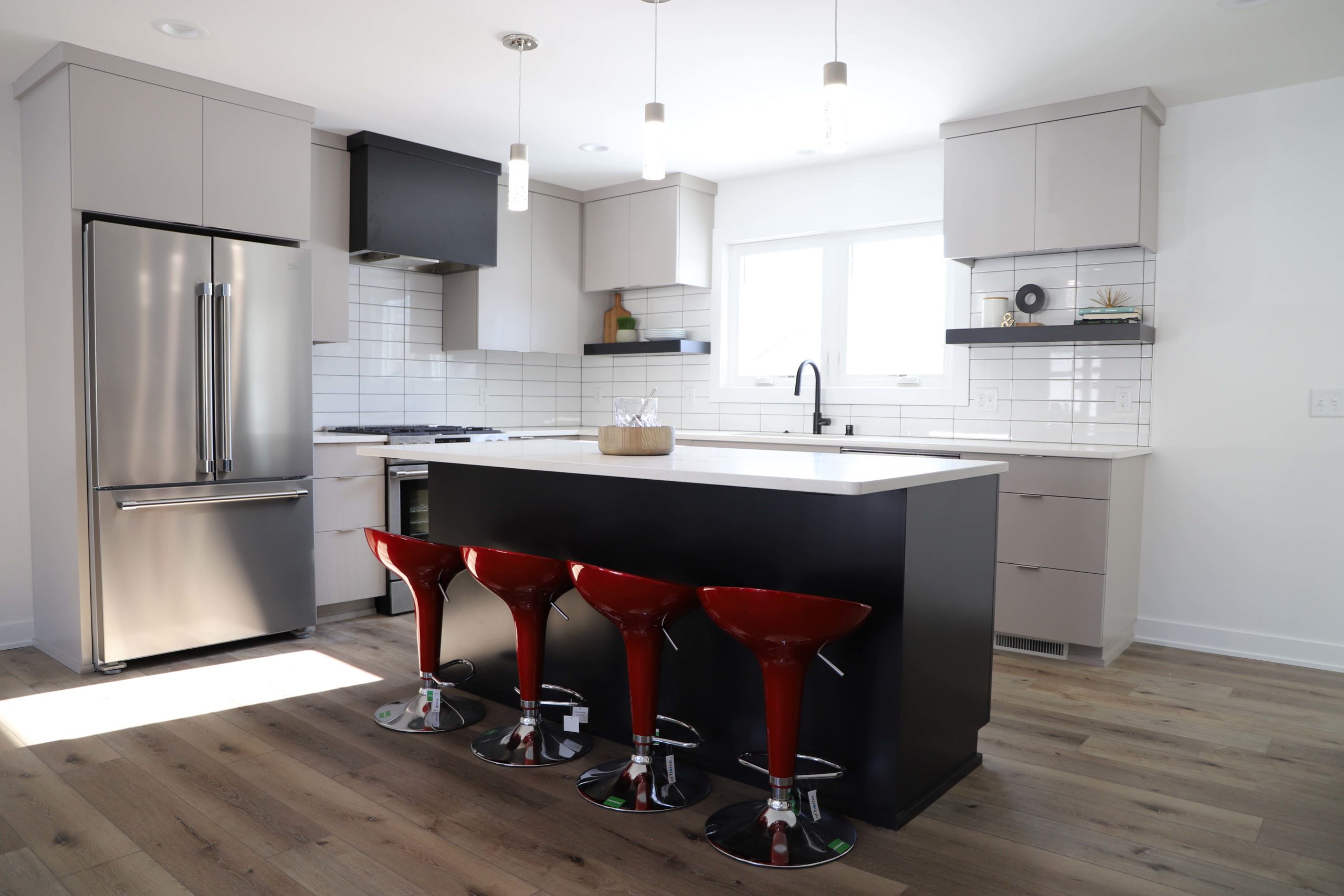 A kitchen with red stools and a black island.