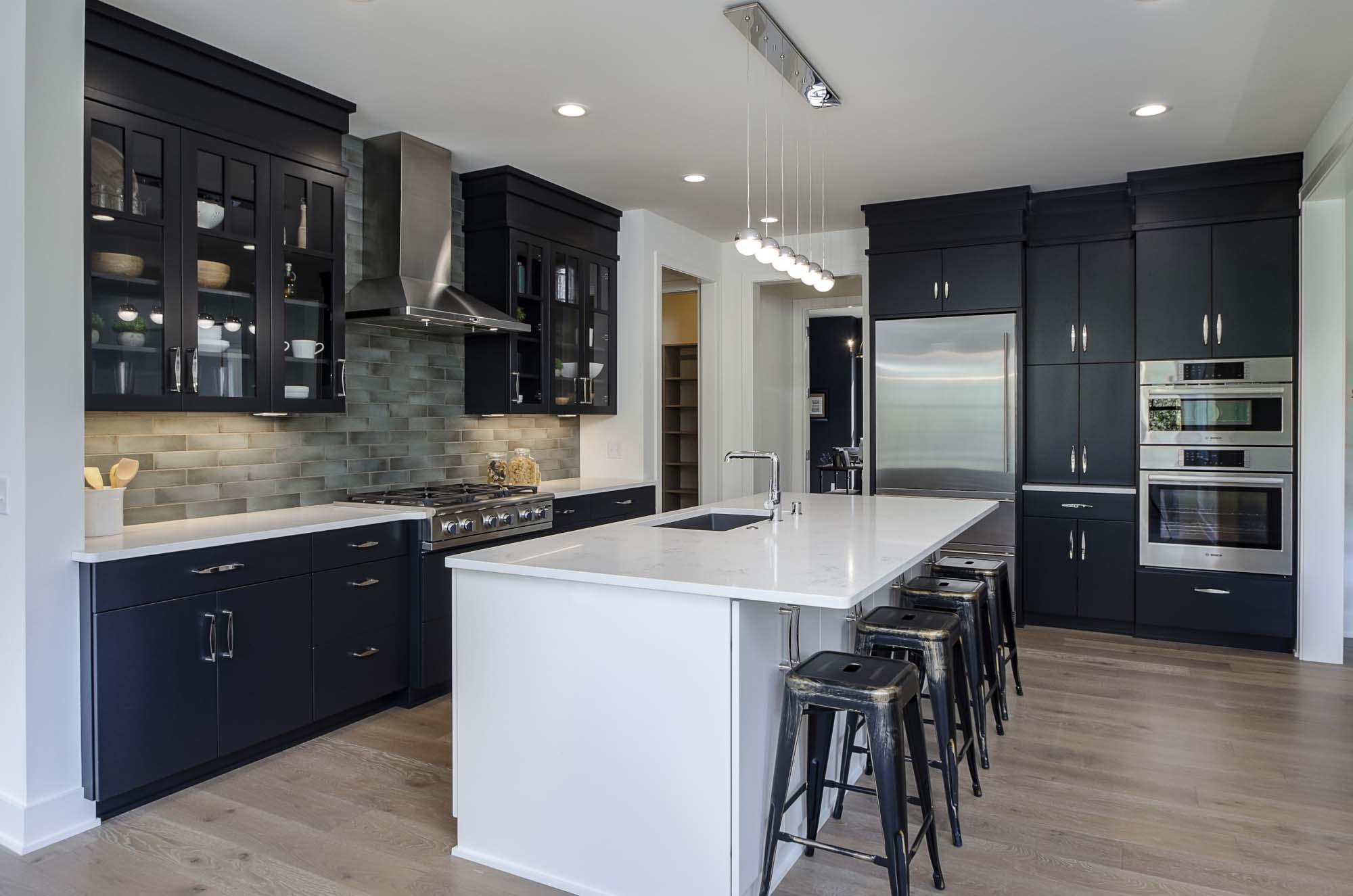 A modern kitchen with black cabinets and a center island.