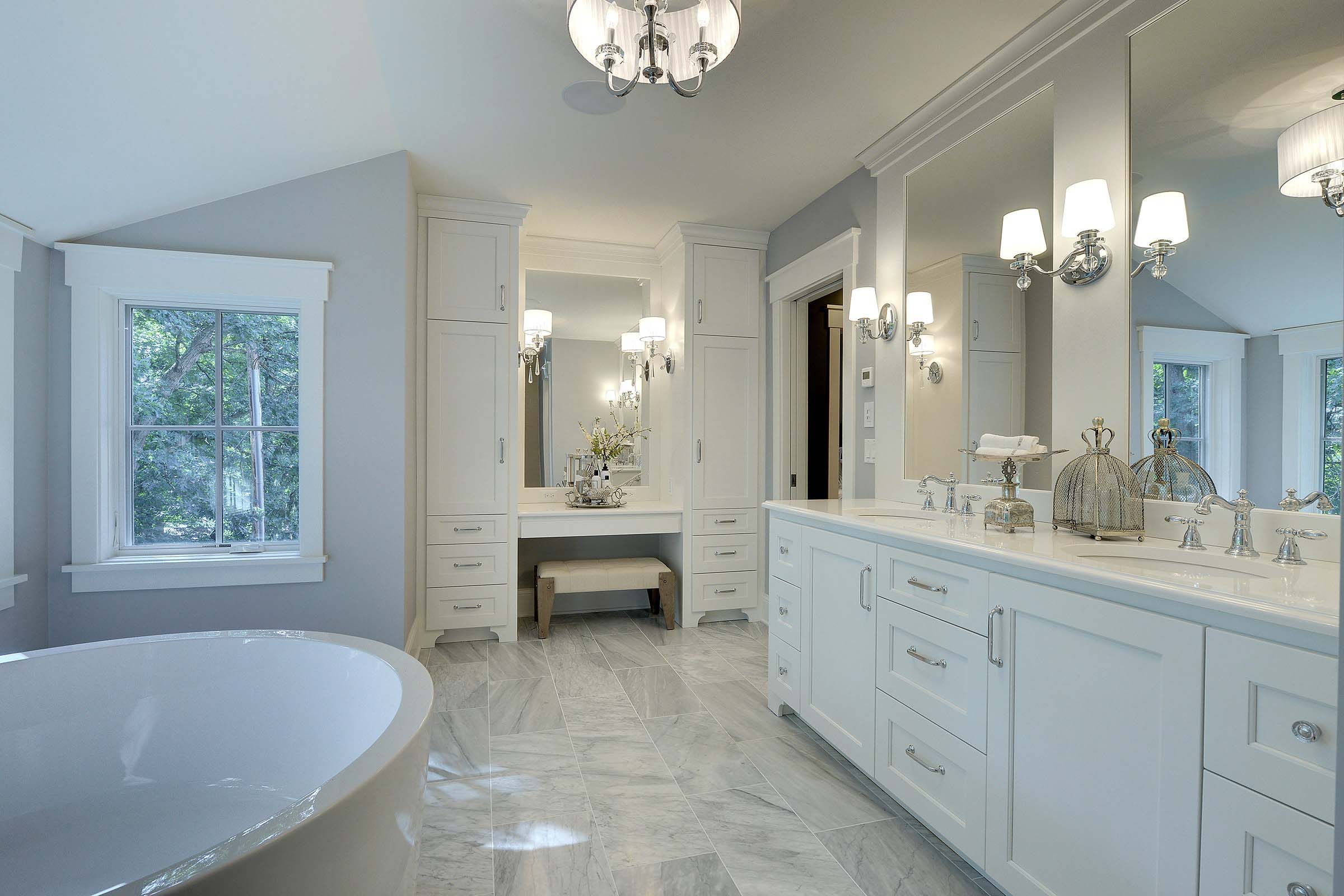 A large bathroom with white cabinets and a large tub.