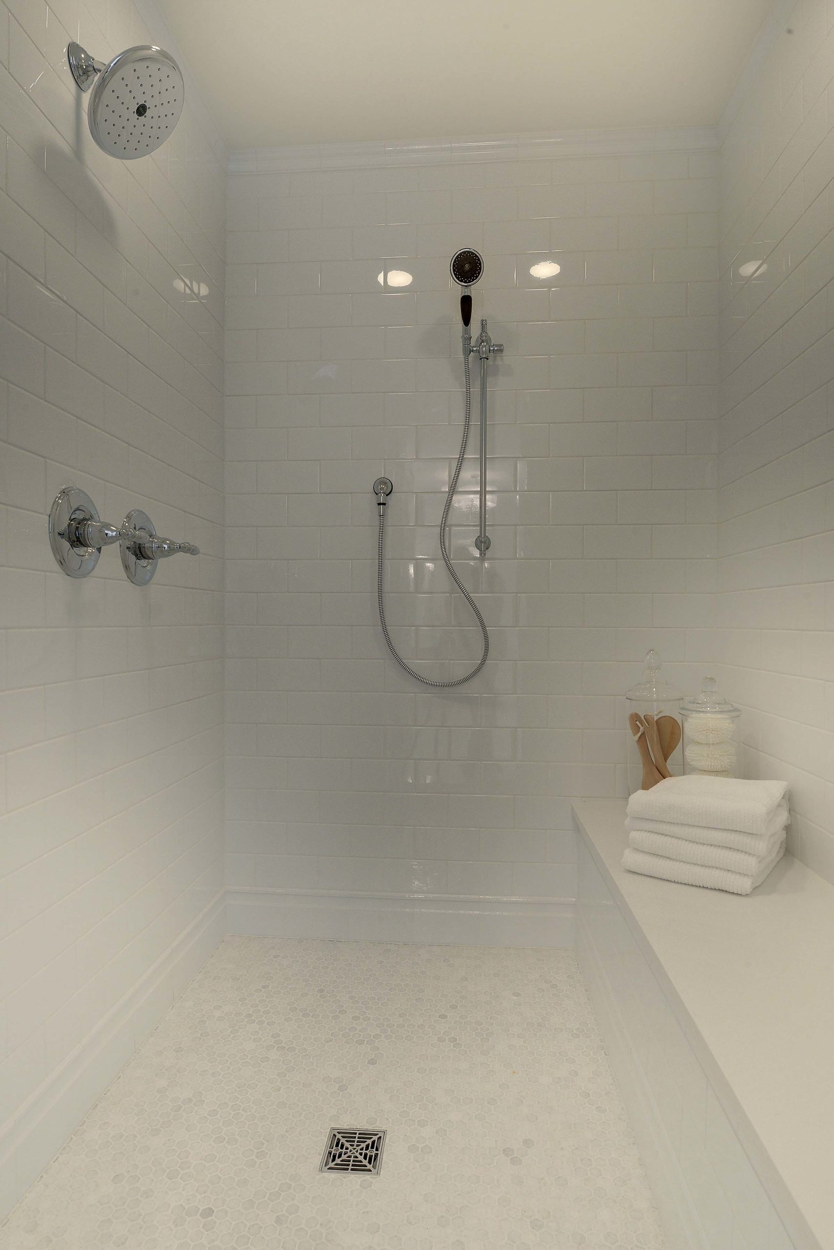 A white shower with a bench and shower head.