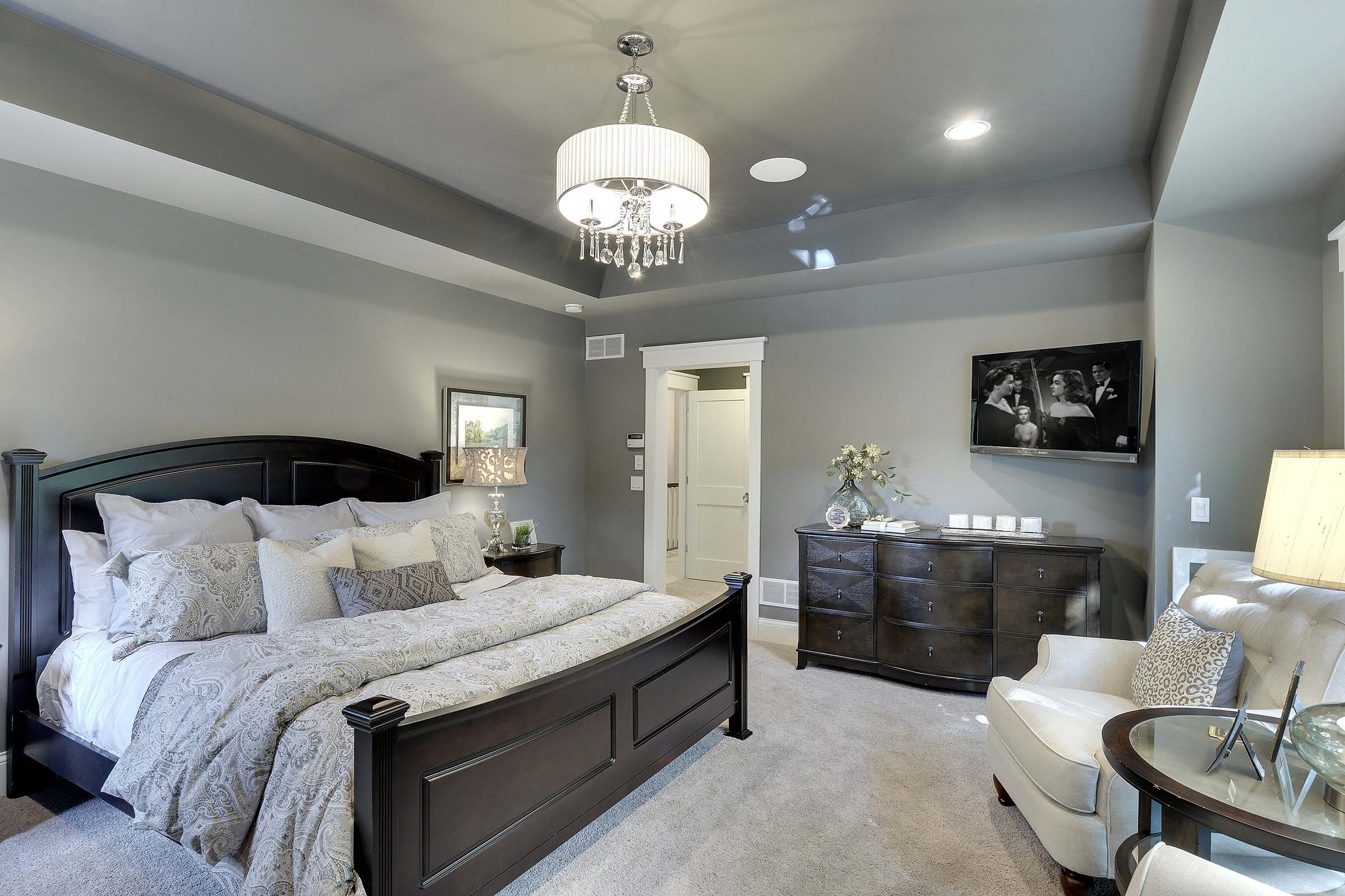 A bedroom with a bed, dresser, and a chandelier.