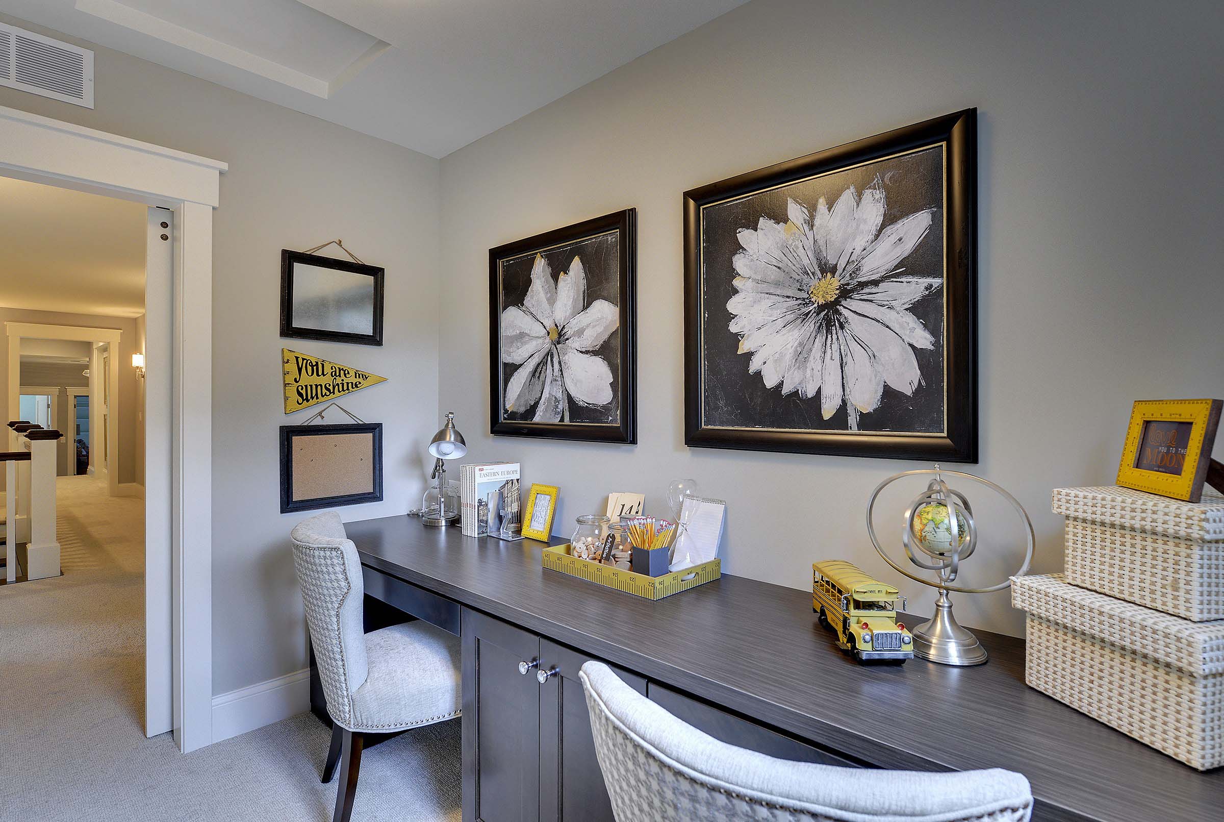 A home office with a desk and framed pictures.