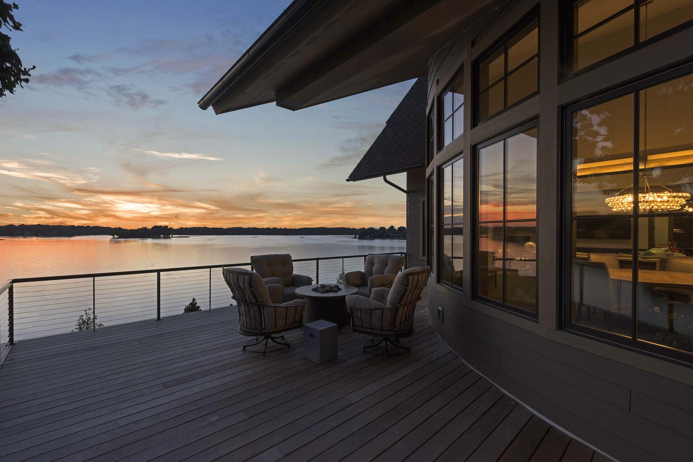 A tranquil deck overlooking a picturesque lake at sunset, offering inspiring home exterior design ideas.