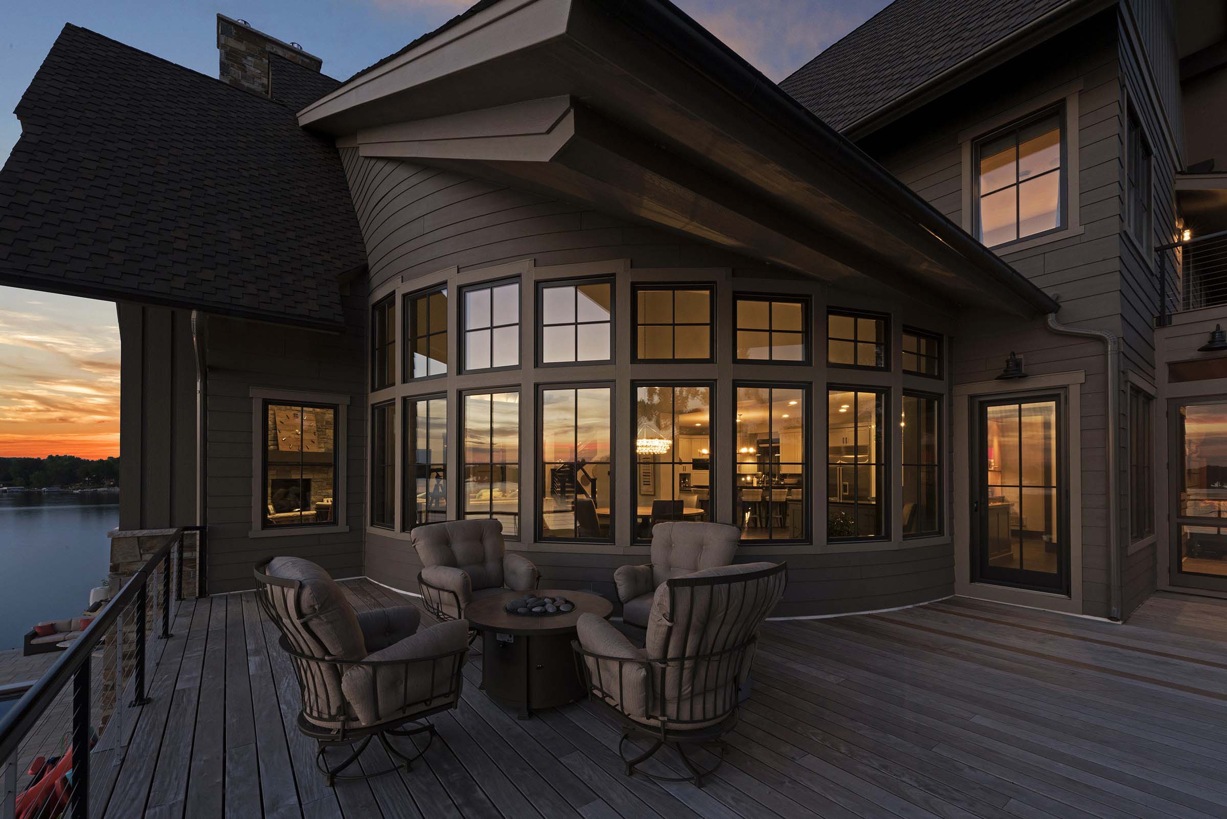 A house with a deck overlooking a lake at dusk, showcasing exceptional home exterior design ideas.