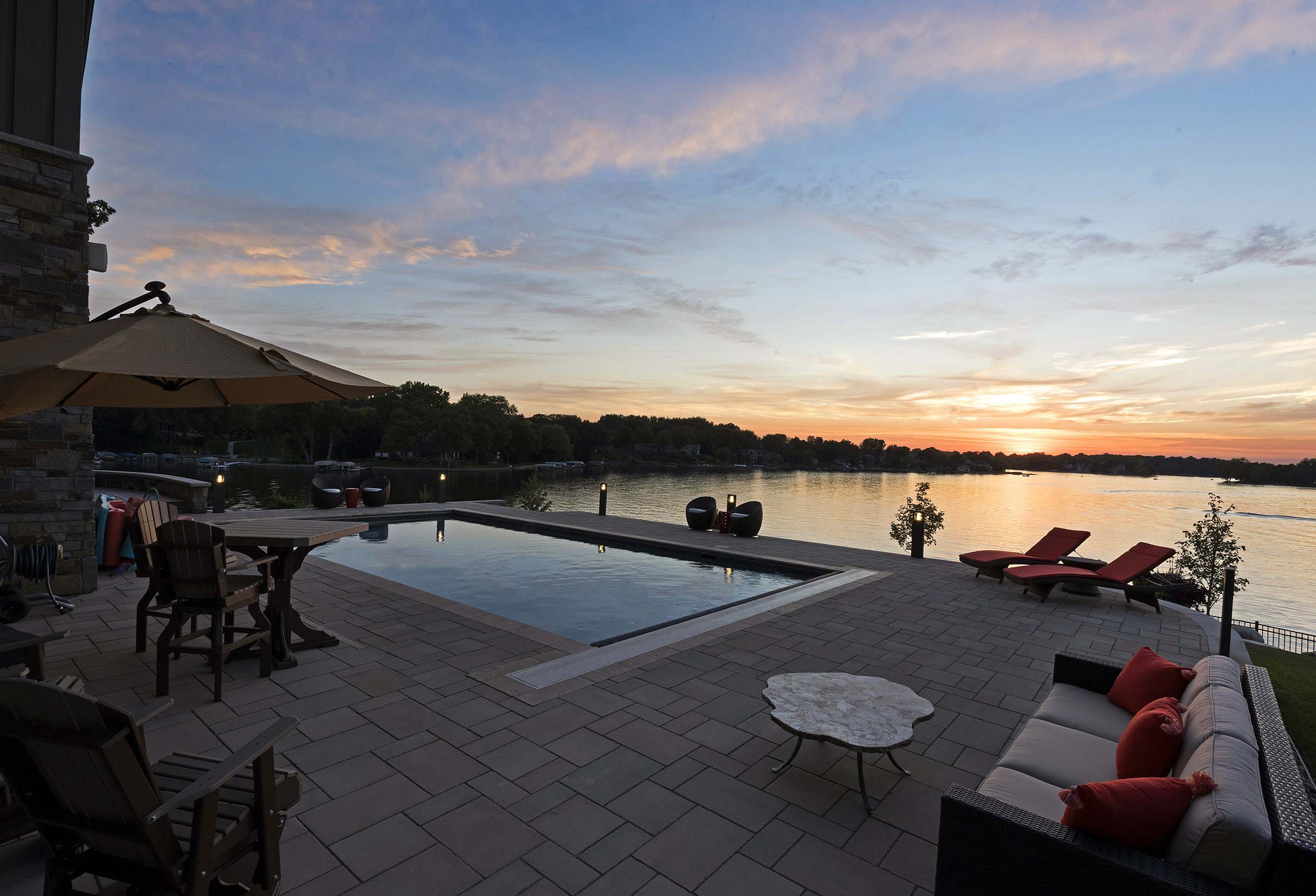 Sunset view from a large pool with multiple seating areas near the lake.