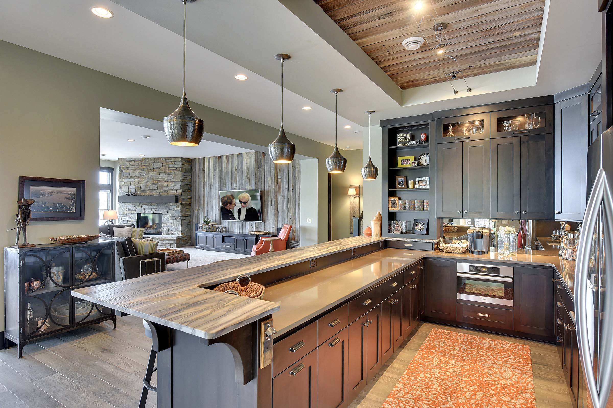 Modern kitchen with rustic hardwood floors, wood inset ceiling and plenty of seating at the counter.