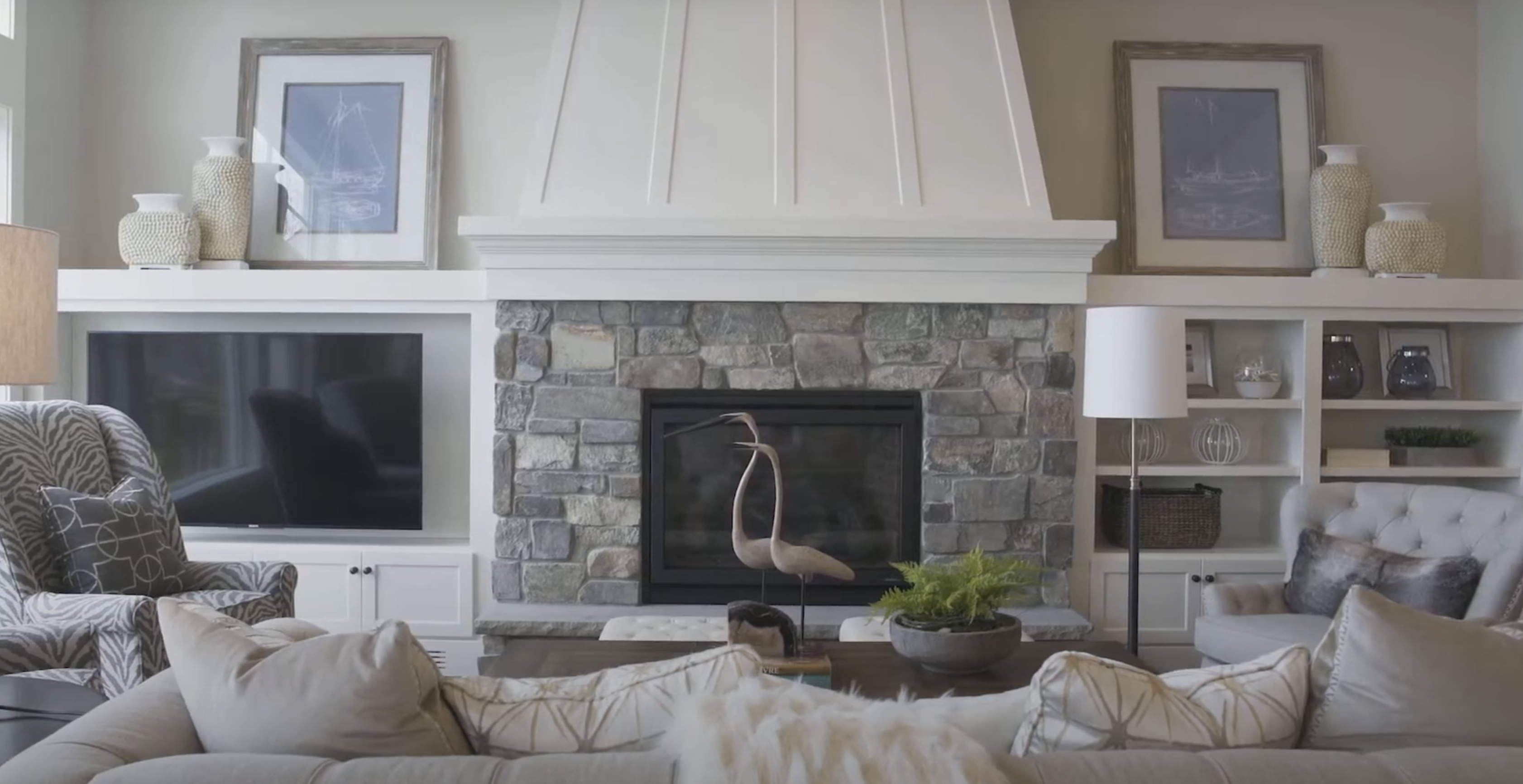 A living room with a stone fireplace and white furniture.