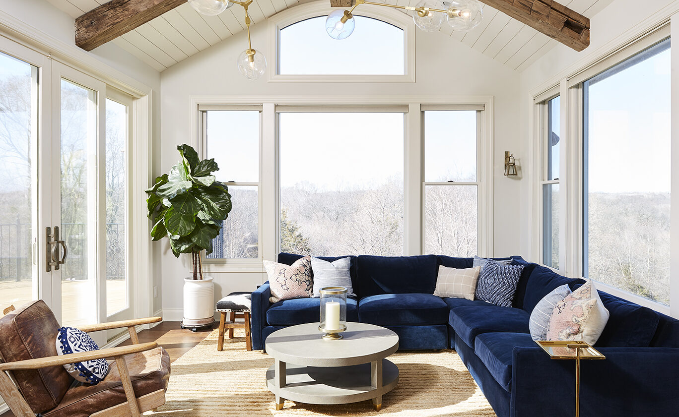 A living room with a blue couch and wooden beams.